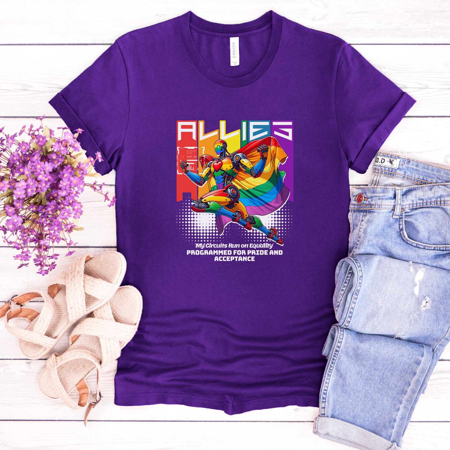 Purple t-shirt with a colorful graphic and text on a wooden surface with flowers and jeans. allies robot shirt, pride shirt, ally shirt, LGBTQ support tee, rainbow graphic tee, equality shirt, acceptance shirt, unisex graphic tee, pride apparel, colorful robot shirt, statement tee, allyship apparel, inclusive fashion, fun pride shirt, rainbow ally shirt