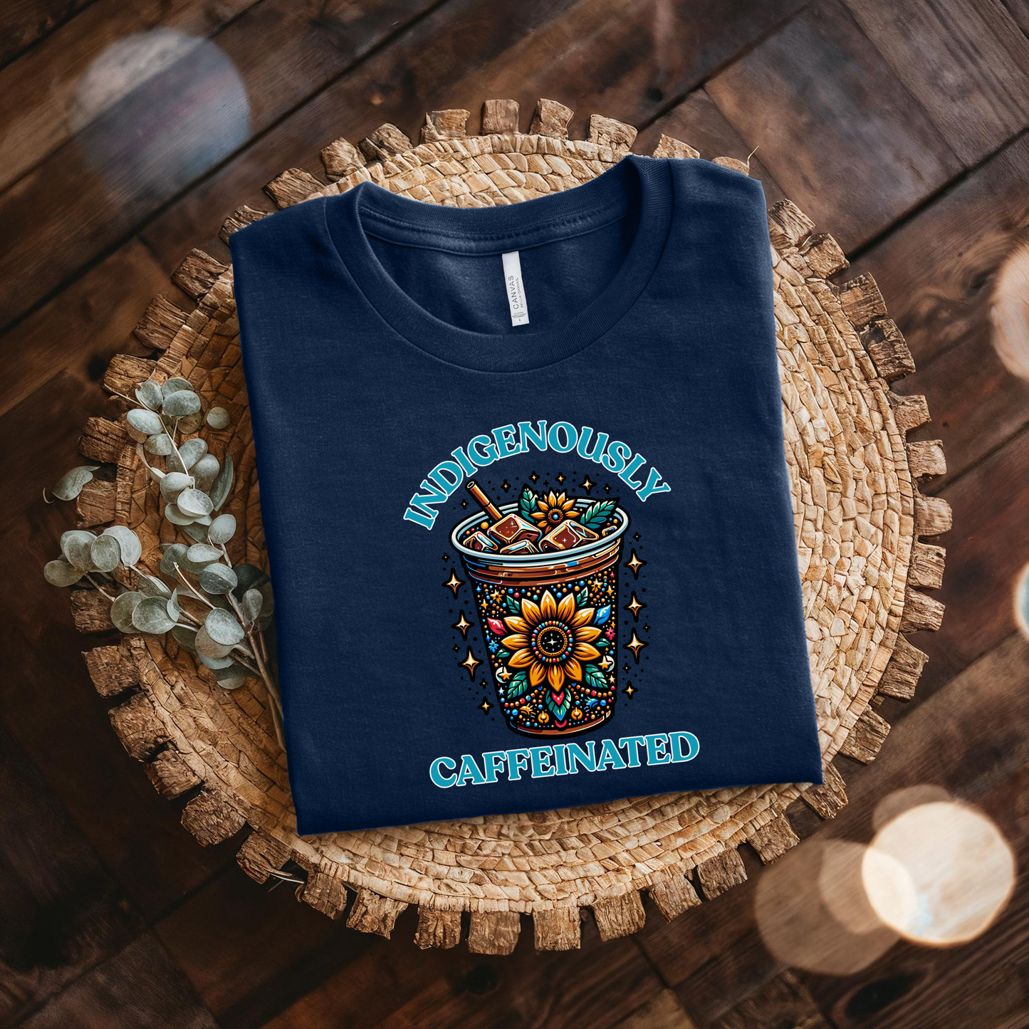 t-shirt featuring a vibrant Indigenous-inspired floral iced coffee design with the phrase "Indigenously Caffeinated" in turquoise lettering. indigenously caffeinated shirt, indigenous coffee lover shirt, indigenous graphic tee, native coffee shirt, coffee lover apparel, indigenous pride clothing, floral coffee design shirt, indigenous entrepreneur shirt, caffeine lover gift, indigenous fashion canada, indigenous art t-shirt, iced coffee graphic tee, indigenous gift ideas, coffee addict shirt, indigenous sma