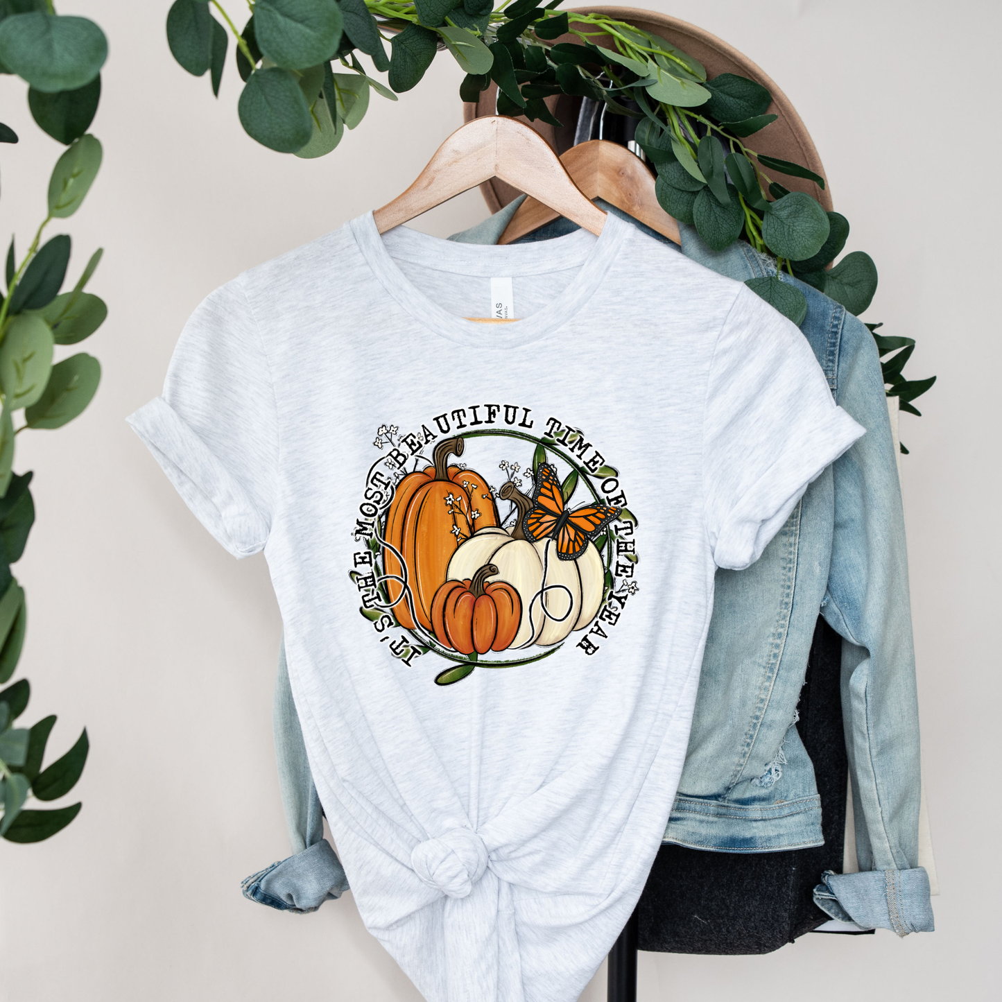 unisex t-shirt featuring pumpkins, a monarch butterfly, leafy accents, and the phrase "It's The Most Beautiful Time Of The Year" in a circular autumn-inspired design. it's the most beautiful time of the year shirt, fall shirt, autumn shirt, pumpkin shirt, pumpkin season shirt, thanksgiving shirt, fall graphic tee, cozy autumn shirt, pumpkin patch shirt, sweater weather shirt, fall aesthetic, harvest shirt, halloween shirt, pumpkin lover gift, autumn outfit, farmhouse fall decor shirt, monarch butterfly