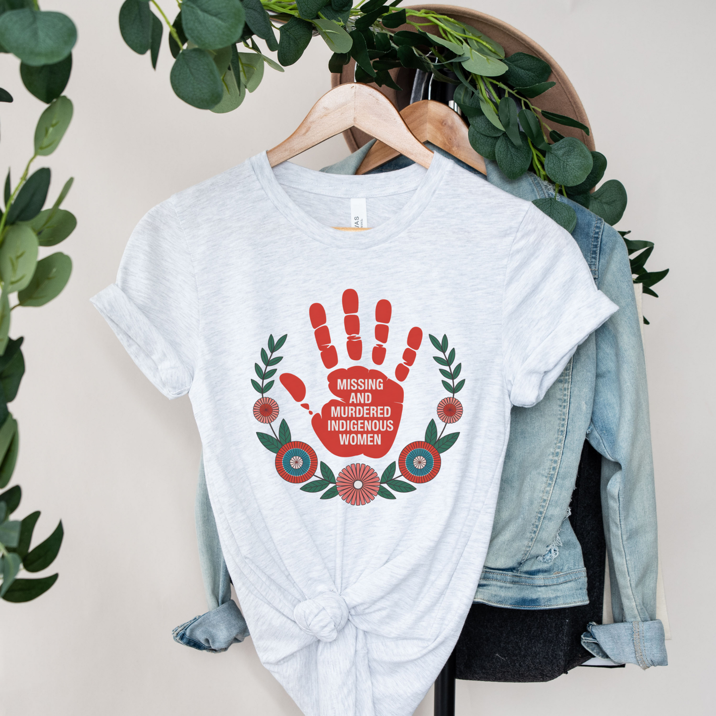 White t-shirt with a red handprint design and text on a hanger with greenery. MMIW shirt, Missing and Murdered Indigenous Women shirt, red handprint shirt, Indigenous awareness shirt, Indigenous rights shirt, MMIW awareness tee, solidarity shirt, social justice shirt, unisex awareness shirt, Canada Indigenous shirt, Indigenous activism clothing, reconciliation shirt, advocate shirt, meaningful graphic tee, awareness apparel