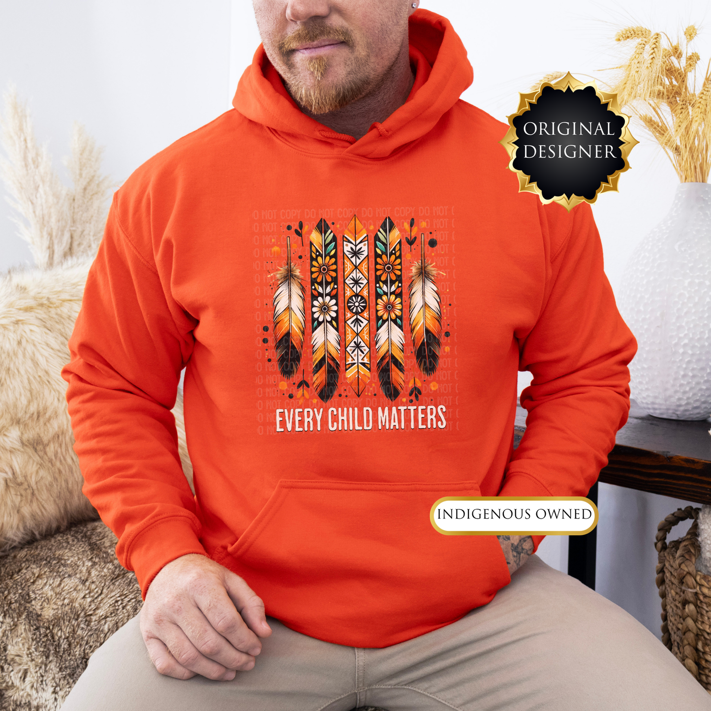 Person wearing an orange hoodie with a design and text, sitting indoors. every child matters hoodie, adult hoodie, orange shirt day hoodie, feathers hoodie, indigenous awareness hoodie, truth and reconciliation hoodie, every child matters pullover, orange pullover, meaningful hoodie, indigenous designed apparel, adult graphic hoodie, orange shirt society licensed, awareness hoodie, remembrance hoodie, indigenous owned business