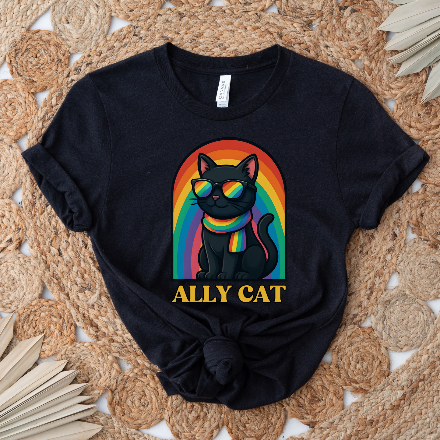 Black t-shirt with a colorful cat graphic and 'ALLY CAT' text on a woven mat background ally cat shirt, rainbow cat shirt, LGBTQ ally shirt, pride cat tee, allyship shirt, cat lover shirt, unisex graphic tee, rainbow shirt, pride apparel, support LGBTQ, fun ally tee, colorful cat shirt, statement tee, cat graphic shirt, inclusive clothing