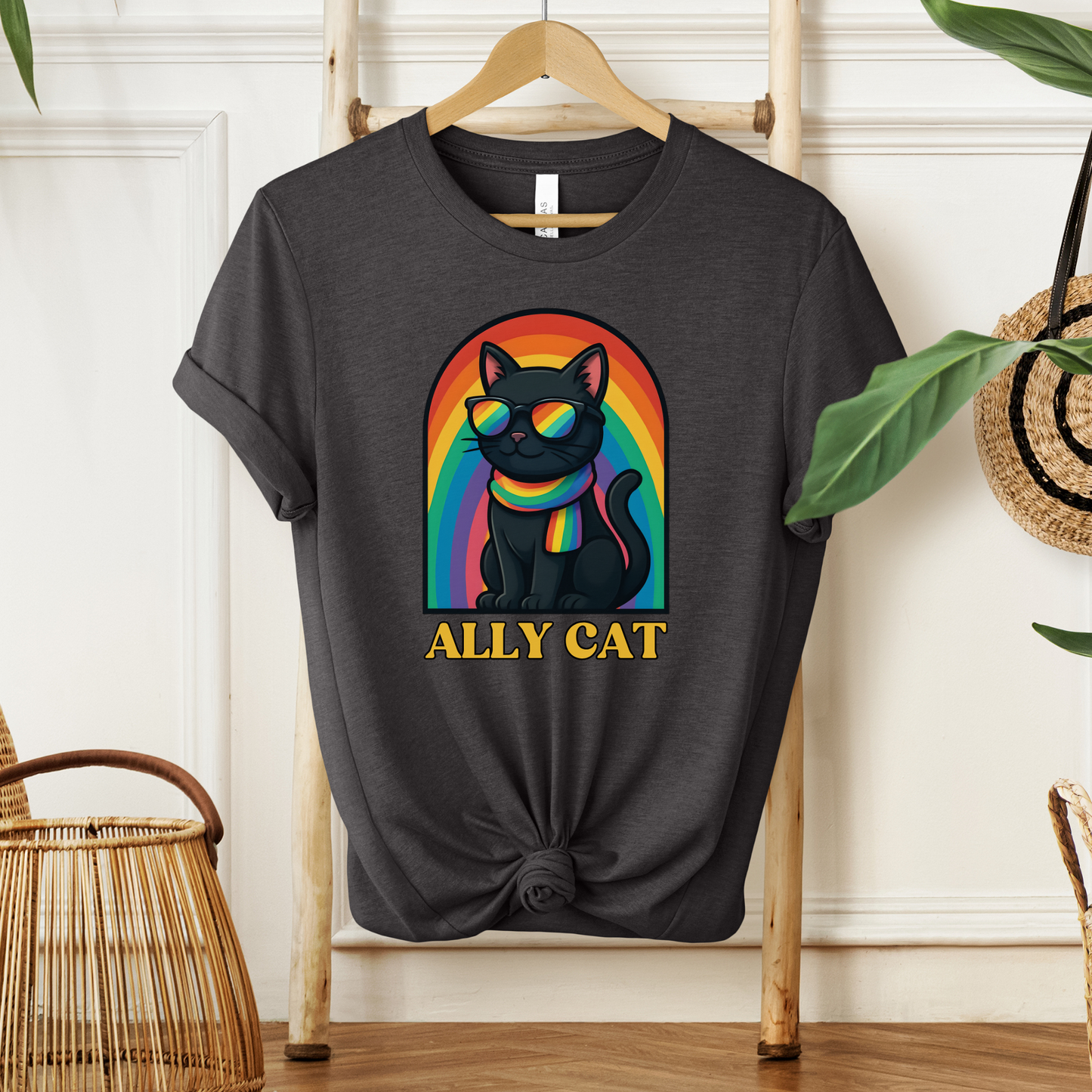 Black t-shirt with a colorful cat graphic and 'ALLY CAT' text on a wooden hanger. ally cat shirt, rainbow cat shirt, LGBTQ ally shirt, pride cat tee, allyship shirt, cat lover shirt, unisex graphic tee, rainbow shirt, pride apparel, support LGBTQ, fun ally tee, colorful cat shirt, statement tee, cat graphic shirt, inclusive clothing