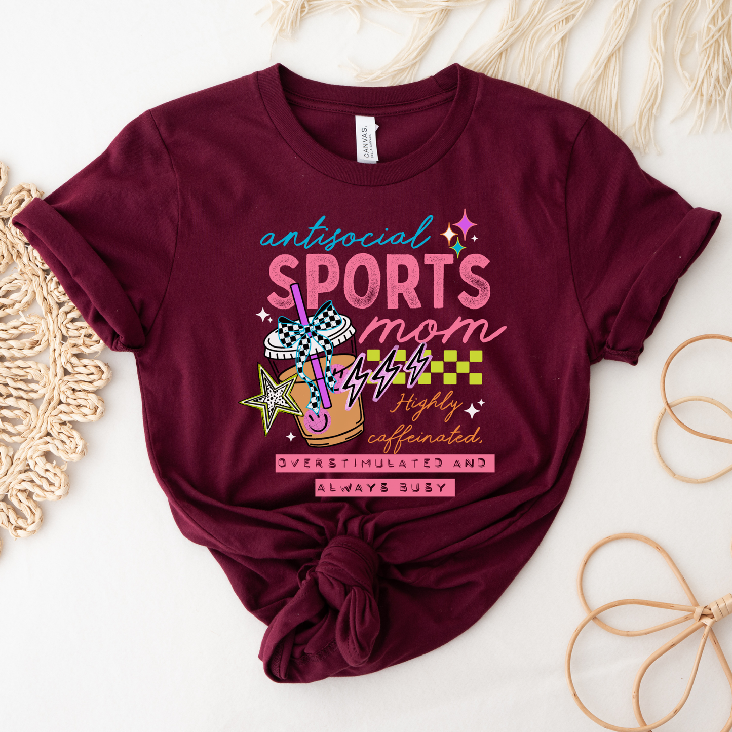 Antisocial Sports Mom Highly Caffeinated Overstimulated And Always Busy shirt with colorful sporty graphic on a unisex tee. antisocial sports mom, sports mom shirt, funny mom tee, caffeinated mom shirt, busy mom apparel, unisex graphic tee, overstimulated mom shirt, sideline mom shirt, coffee mom shirt, statement tee, mom life shirt, everyday casual tee, gift for sports mom, humorous mom shirt, colorful graphic tee