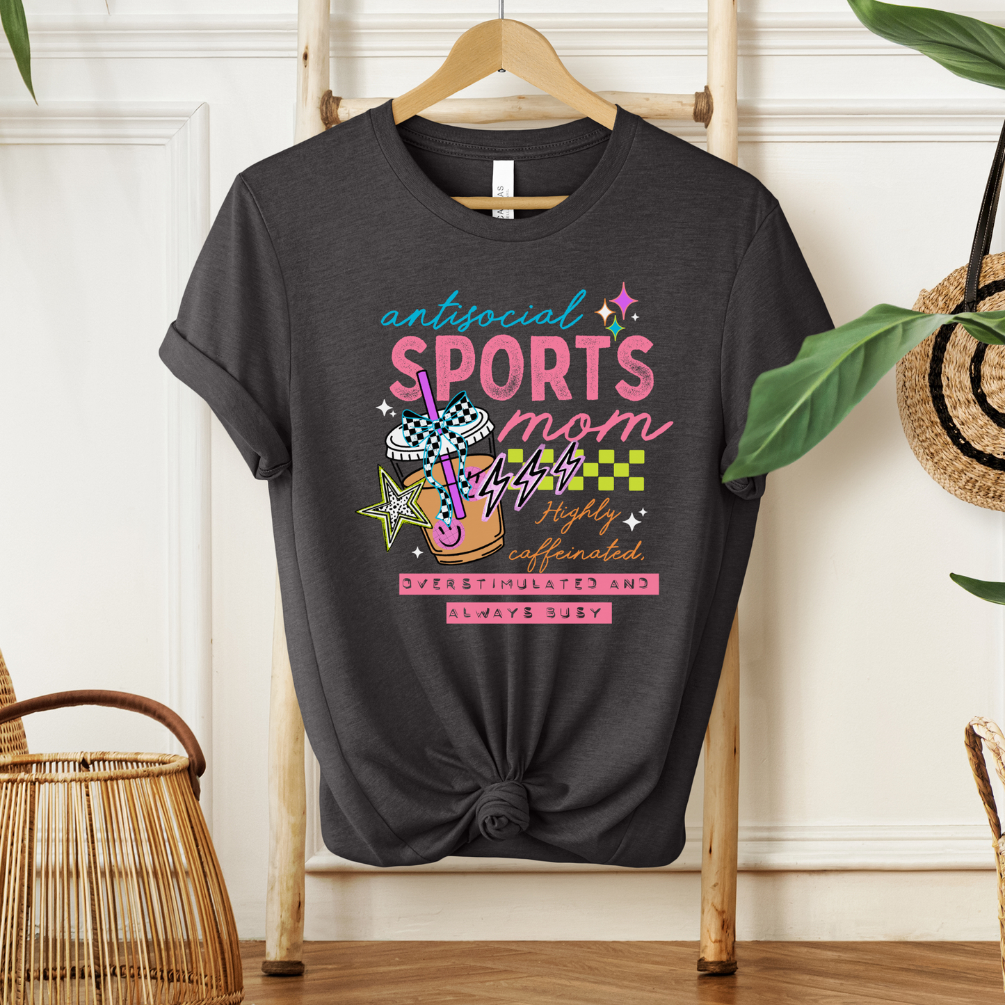 Antisocial Sports Mom Highly Caffeinated Overstimulated And Always Busy shirt with colorful sporty graphic on a unisex tee. antisocial sports mom, sports mom shirt, funny mom tee, caffeinated mom shirt, busy mom apparel, unisex graphic tee, overstimulated mom shirt, sideline mom shirt, coffee mom shirt, statement tee, mom life shirt, everyday casual tee, gift for sports mom, humorous mom shirt, colorful graphic tee