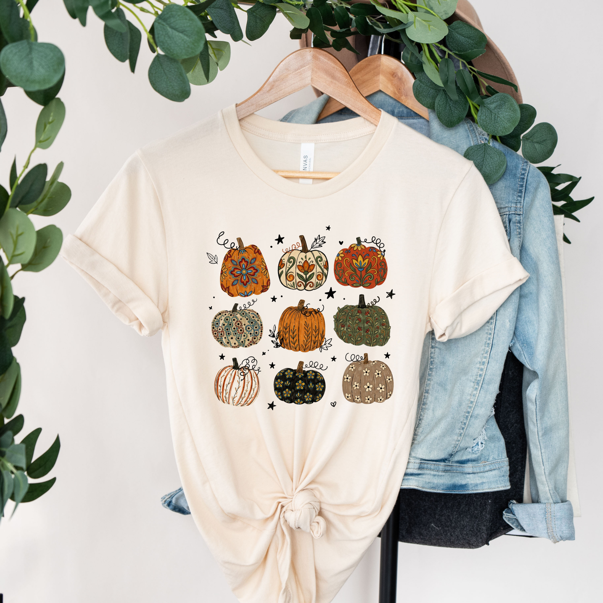 t-shirt featuring nine decorative pumpkins with Indigenous-inspired floral and botanical patterns in warm autumn colors arranged in a grid. indigenous pumpkin shirt, boho pumpkin shirt, fall pumpkin shirt, autumn graphic tee, thanksgiving shirt, indigenous inspired shirt, floral pumpkin shirt, woodland fall shirt, pumpkin patch outfit, harvest shirt, boho fall fashion, cozy autumn tee, fall aesthetic shirt, pumpkin lover gift, autumn apparel, cottagecore fall shirt, botanical pumpkin shirt
