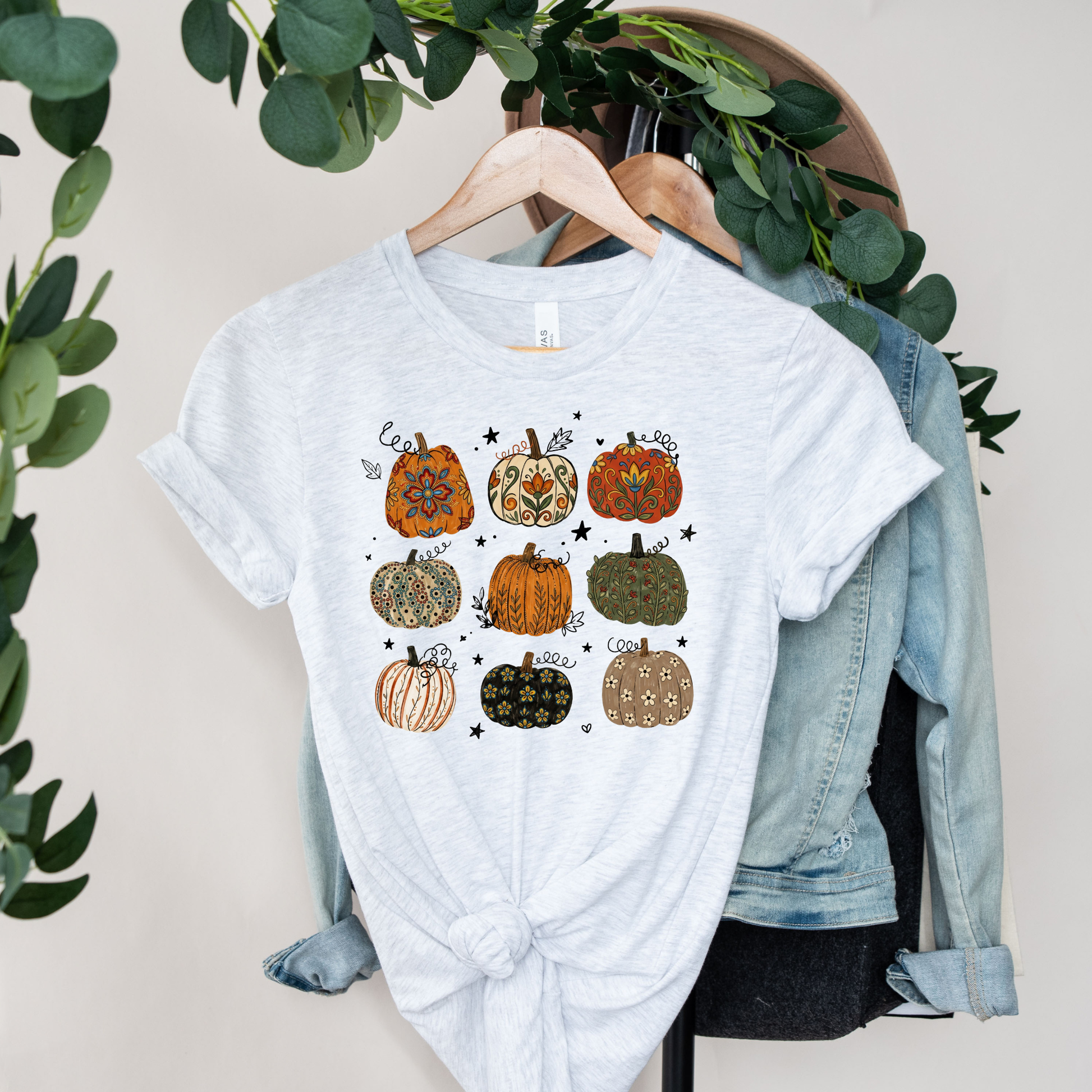 t-shirt featuring nine decorative pumpkins with Indigenous-inspired floral and botanical patterns in warm autumn colors arranged in a grid. indigenous pumpkin shirt, boho pumpkin shirt, fall pumpkin shirt, autumn graphic tee, thanksgiving shirt, indigenous inspired shirt, floral pumpkin shirt, woodland fall shirt, pumpkin patch outfit, harvest shirt, boho fall fashion, cozy autumn tee, fall aesthetic shirt, pumpkin lover gift, autumn apparel, cottagecore fall shirt, botanical pumpkin shirt