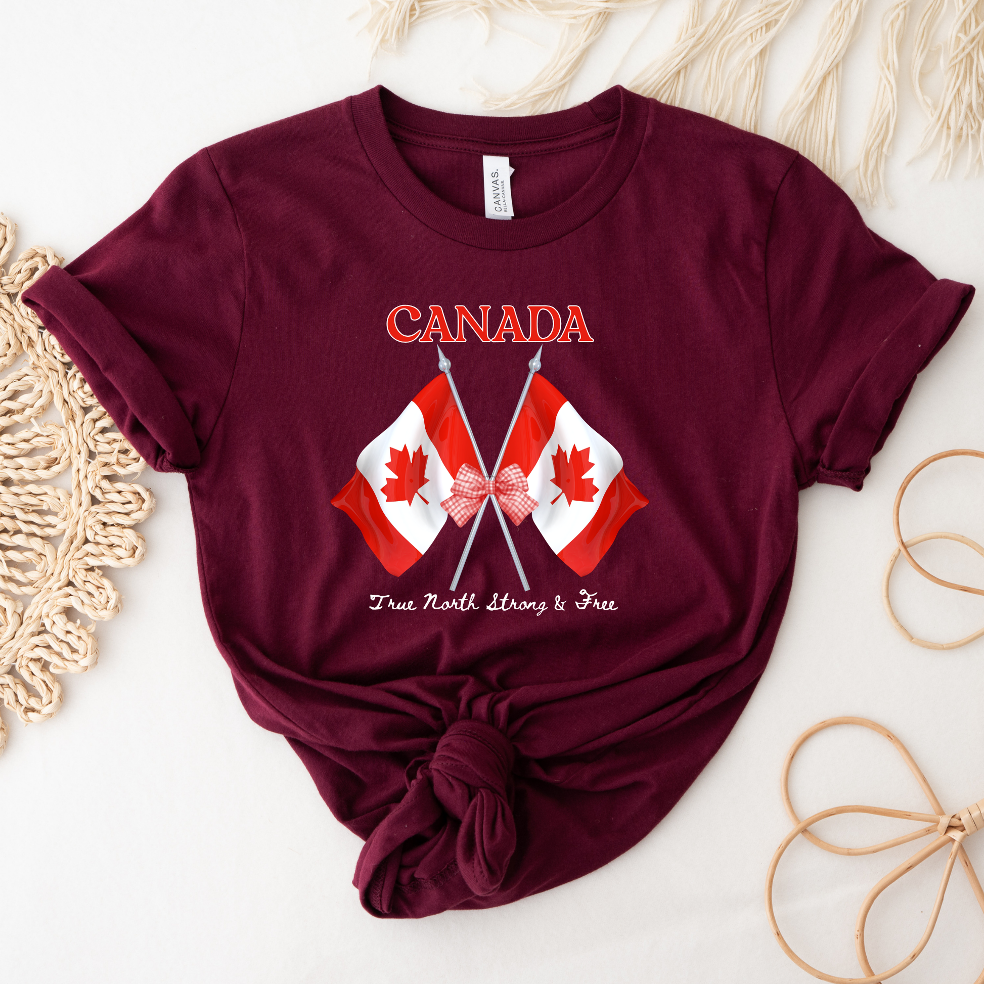 Canada Day Flag Coquette Bow True North Strong and Free Shirt featuring two Canadian flags with a red gingham bow and patriotic Canadian design. canada day shirt, canada shirt, canadian pride shirt, true north strong and free, coquette bow shirt, canada flag shirt, patriotic canada shirt, canada day outfit, canada day apparel, gingham bow shirt, july 1st shirt, canadian clothing, red bow shirt, canada celebration shirt, canadian gift, cute canada shirt, canada day tee, canada flag bow, canada coquette shirt