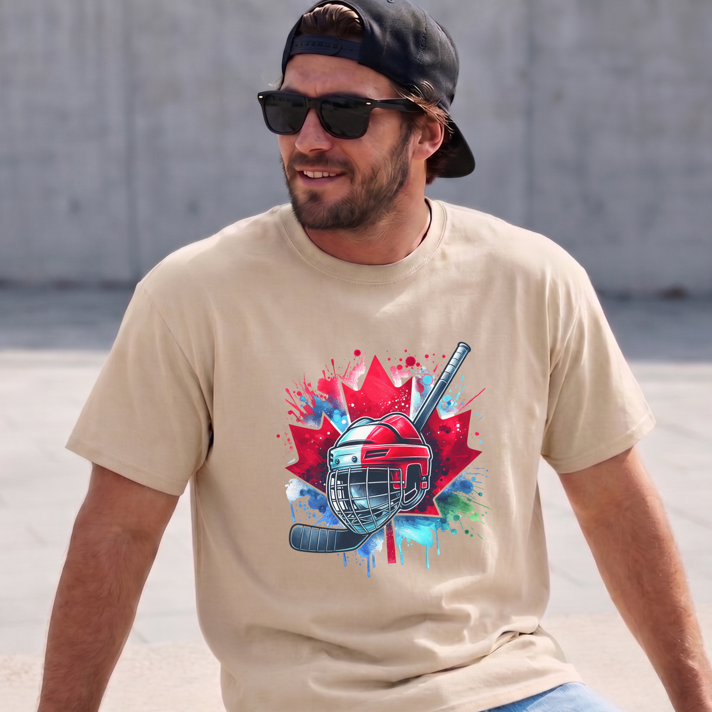 Canada Hockey Shirt featuring a colorful hockey helmet and stick graphic layered over a vibrant red Canadian maple leaf with paint splash accents. Proudly made in Canada, this patriotic hockey t-shirt is perfect for hockey fans, players, coaches, and Canada Day celebrations.
