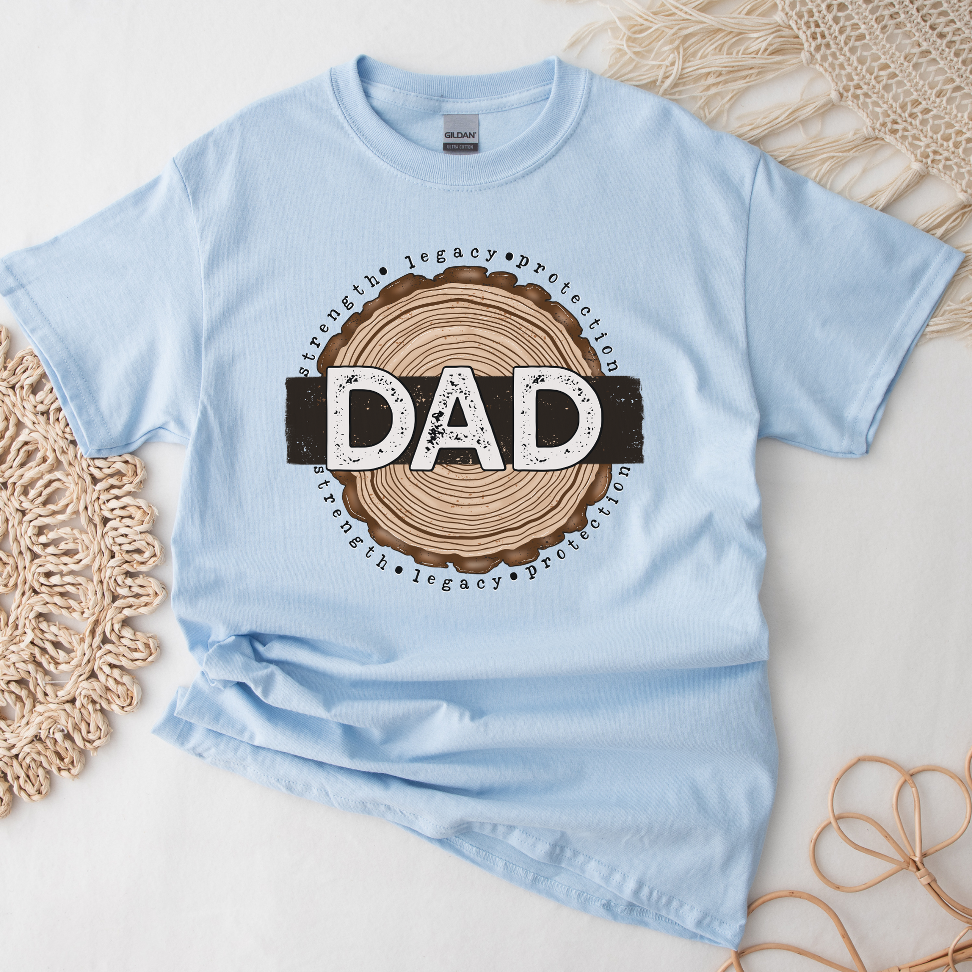 Dad shirt with woodgrain design and the words strength, legacy, protection on a unisex t-shirt. dad shirt, strength legacy protection, father shirt, unisex graphic tee, father’s day shirt, meaningful dad tee, rustic dad shirt, family apparel, dad gift, masculine graphic tee, everyday wear shirt, bold dad design, protective father shirt, legacy shirt, dad lifestyle tee