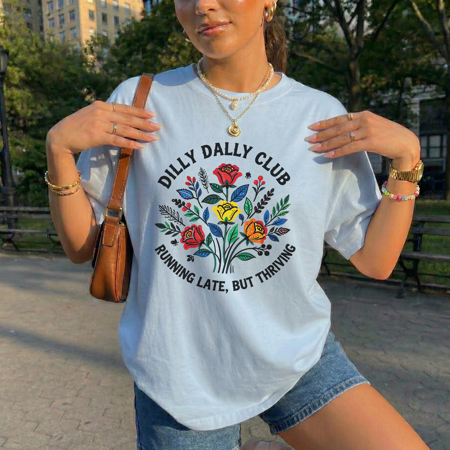 Dilly Dally Club Running Late, But Thriving shirt design featuring colorful woodland-inspired floral artwork with red, yellow, orange, blue, and green flowers arranged in a bouquet. Circular text reads 'Dilly Dally Club' and 'Running Late, But Thriving' on a transparent background. Dilly Dally Club, Running Late But Thriving, Woodland Floral, Floral Shirt, Graphic Tee, Funny Shirt, Unisex Tee, Floral Graphic Tee, Indigenous Inspired, Botanical Shirt, Cottagecore Fashion, Colorful Shirt, Gift For Her
