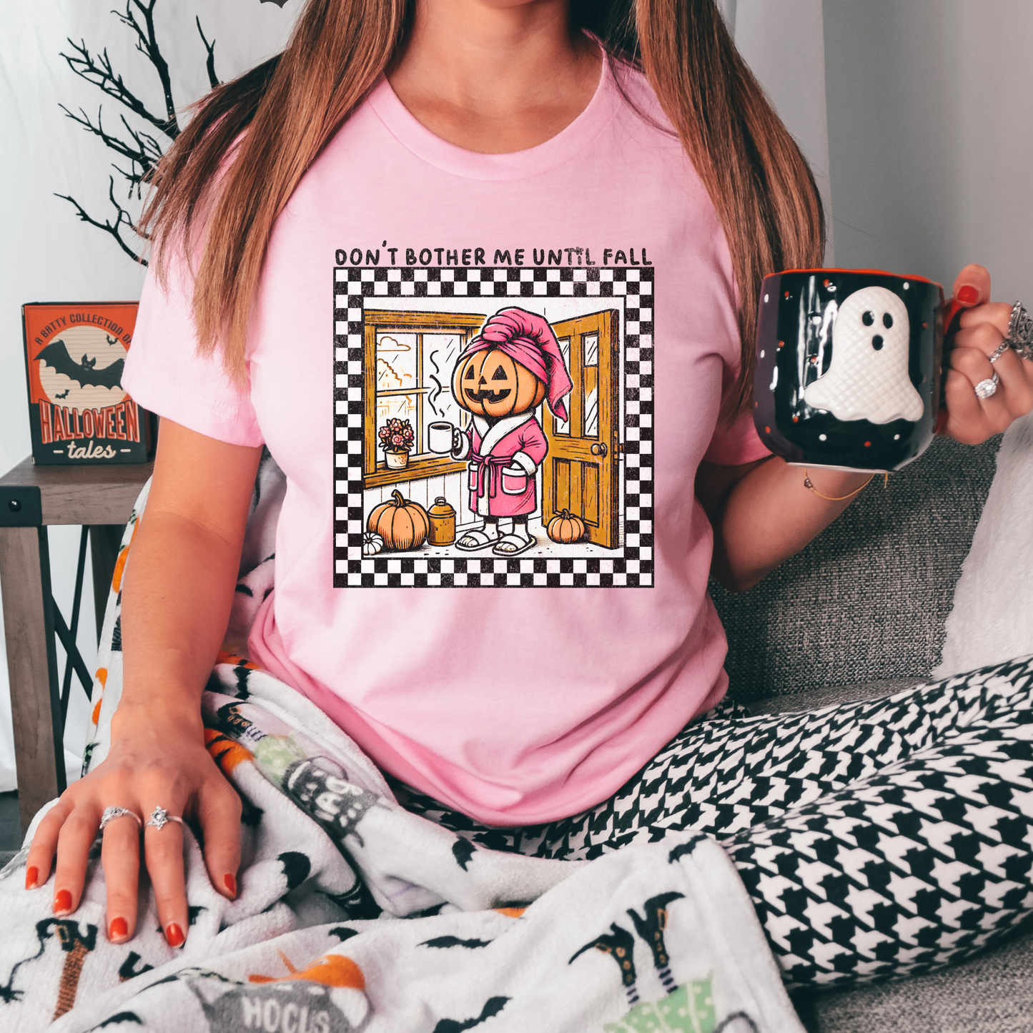 t-shirt featuring a cozy pumpkin character wearing a pink robe and towel, holding a coffee mug with the phrase "Don't Bother Me Until Fall," surrounded by autumn-inspired details and a checkered border. don't bother me until fall shirt, halloween pumpkin shirt, cozy autumn tee, fall lover t-shirt, pumpkin spice season shirt, spooky season apparel, cute pumpkin graphic tee, halloween aesthetic clothing, autumn lover gift, fall festival shirt, pumpkin patch outfit, cozy season clothing, spooky cute graphic te
