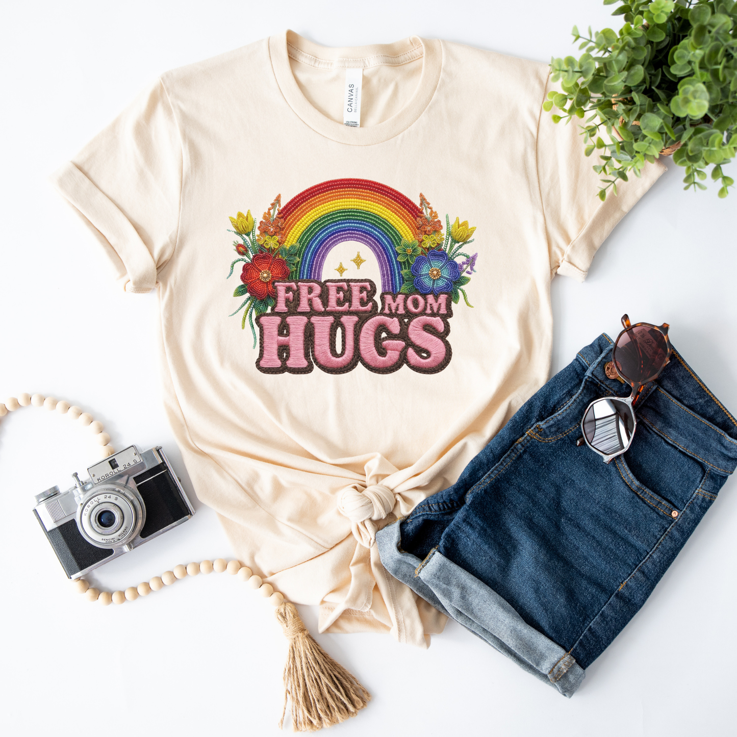 Free Mom Hugs Shirt featuring Indigenous-inspired beaded floral artwork, rainbow design, and pink faux embroidered lettering. free mom hugs shirt, pride shirt, indigenous floral shirt, beaded floral shirt, rainbow pride shirt, lgbtq ally shirt, supportive mom shirt, pride parade shirt, indigenous inspired apparel, faux embroidery shirt, mom hugs shirt, rainbow floral tee, inclusive apparel, pride month shirt, indigenous beadwork design, ally gift, lgbtq support shirt, community love shirt, acceptance shirt