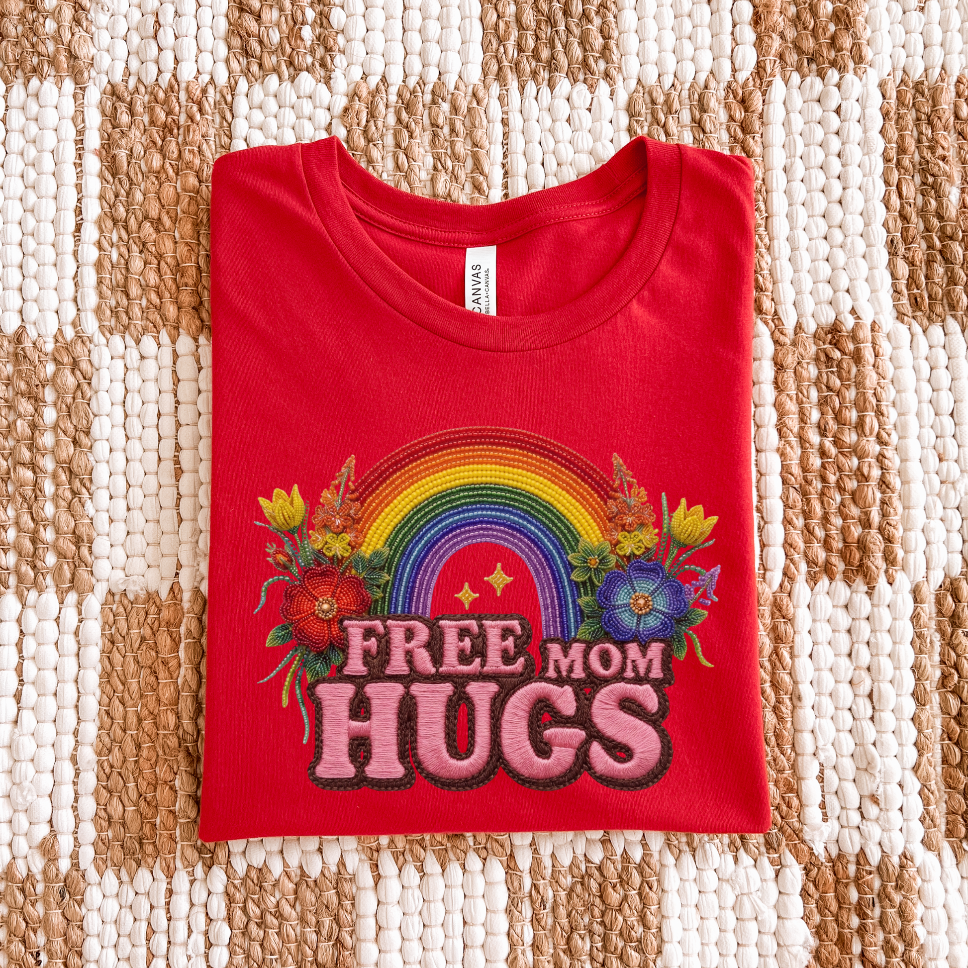 Free Mom Hugs Shirt featuring Indigenous-inspired beaded floral artwork, rainbow design, and pink faux embroidered lettering. free mom hugs shirt, pride shirt, indigenous floral shirt, beaded floral shirt, rainbow pride shirt, lgbtq ally shirt, supportive mom shirt, pride parade shirt, indigenous inspired apparel, faux embroidery shirt, mom hugs shirt, rainbow floral tee, inclusive apparel, pride month shirt, indigenous beadwork design, ally gift, lgbtq support shirt, community love shirt, acceptance shirt
