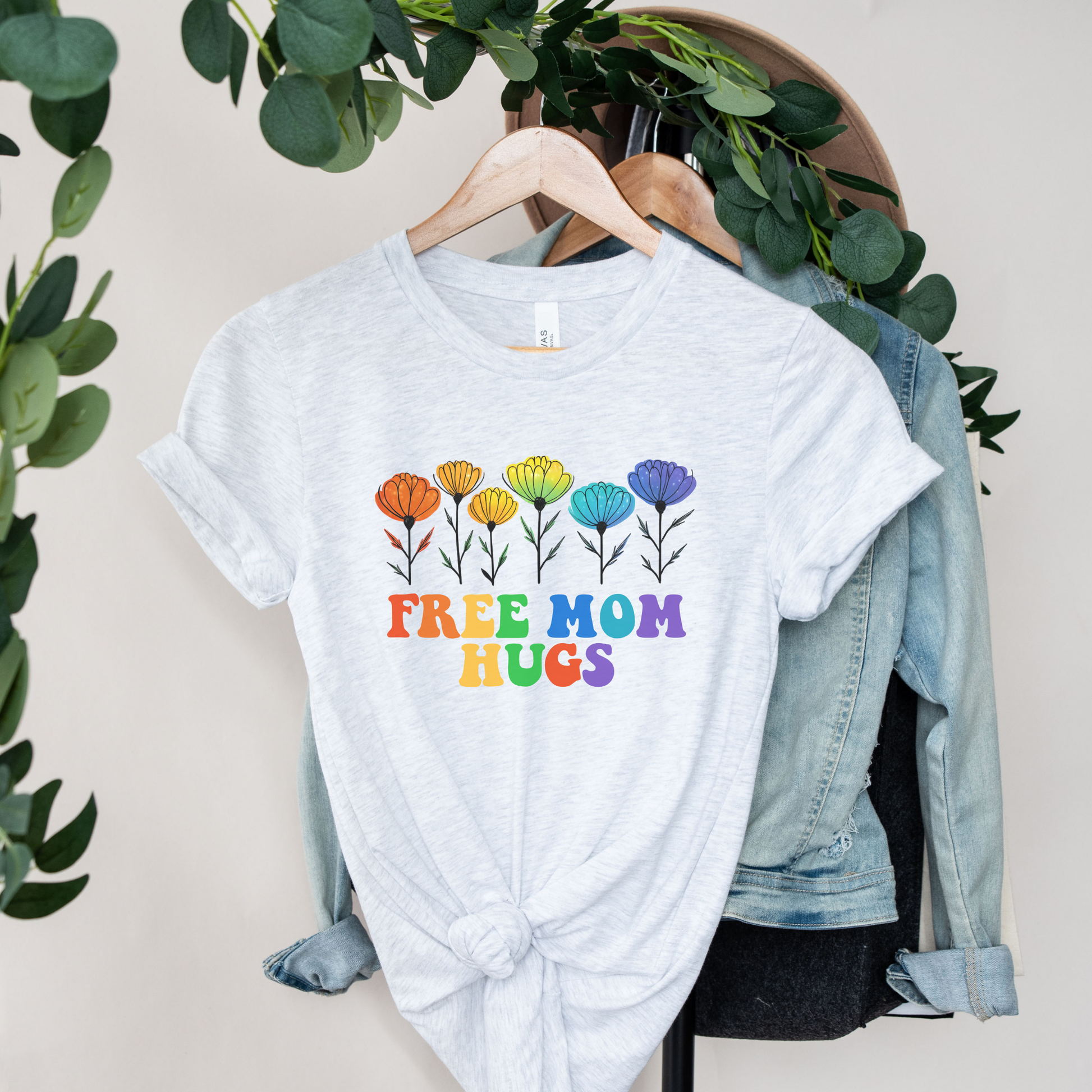 unisex shirt featuring rainbow wildflowers and colourful retro lettering that reads Free Mom Hugs, celebrating LGBTQ2S+ pride, allyship, and inclusion. Free Mom Hugs Shirt, Pride Ally Shirt, LGBTQ2S+ Support Shirt, Rainbow Floral Shirt, Pride Apparel Canada, LGBTQ Ally Tee, Free Hugs Shirt, Rainbow Wildflower Tee, Inclusive Apparel, Pride Month Clothing
