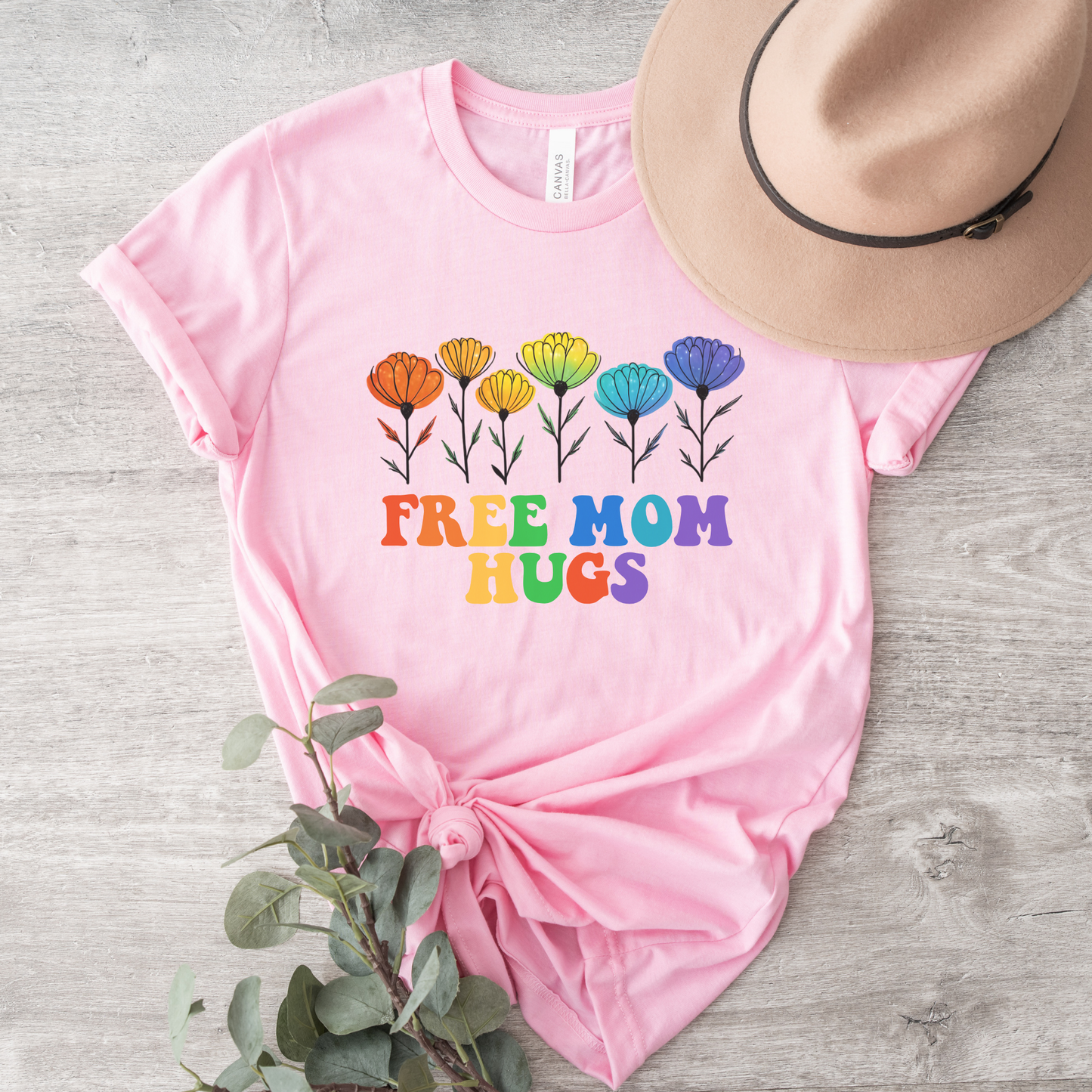 unisex shirt featuring rainbow wildflowers and colourful retro lettering that reads Free Mom Hugs, celebrating LGBTQ2S+ pride, allyship, and inclusion. Free Mom Hugs Shirt, Pride Ally Shirt, LGBTQ2S+ Support Shirt, Rainbow Floral Shirt, Pride Apparel Canada, LGBTQ Ally Tee, Free Hugs Shirt, Rainbow Wildflower Tee, Inclusive Apparel, Pride Month Clothing