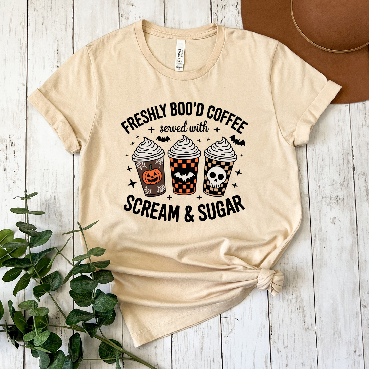 Funny Halloween coffee shirt featuring three festive coffee cups with pumpkins, bats, checkerboard patterns, and skull artwork that reads "Freshly Boo'd Coffee Served With Scream & Sugar." freshly boo'd coffee shirt, scream and sugar shirt, halloween coffee shirt, spooky coffee shirt, coffee lover halloween shirt, pumpkin spice shirt, fall coffee shirt, cute halloween tee, halloween graphic tee, spooky season shirt, pumpkin patch outfit, coffee addict shirt, funny coffee shirt, halloween apparel