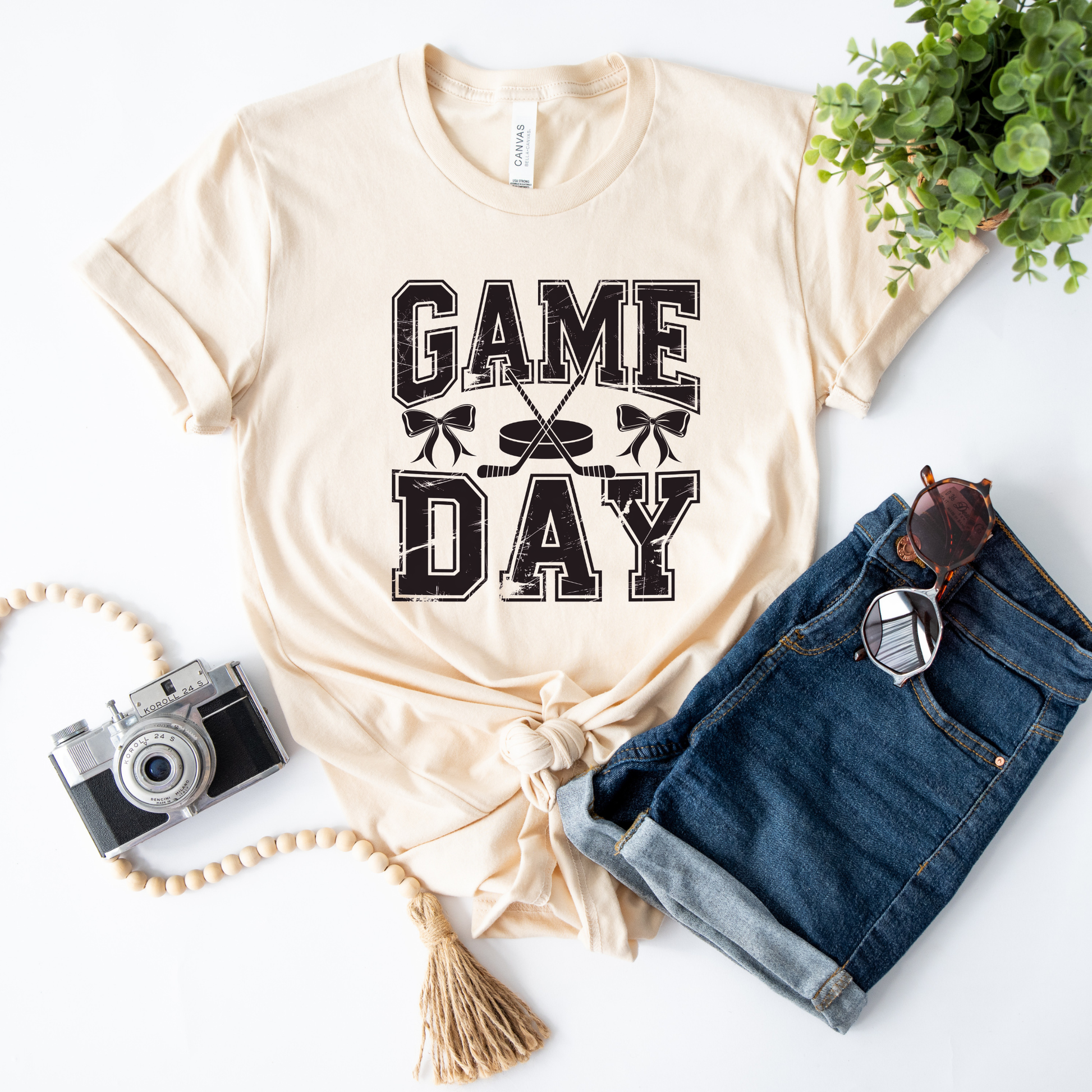 t-shirt featuring distressed varsity lettering that reads "Game Day" with crossed hockey sticks, a puck, and coquette bow accents in a vintage-inspired hockey graphic. game day hockey shirt, hockey coquette shirt, hockey mom shirt, hockey game day tee, bow hockey shirt, hockey girlfriend shirt, hockey sister shirt, hockey fan apparel, varsity hockey shirt, distressed hockey tee, hockey season shirt, hockey lover gift, cute hockey shirt, sports mom shirt, hockey tournament outfit, ice hockey shirt, coquette 