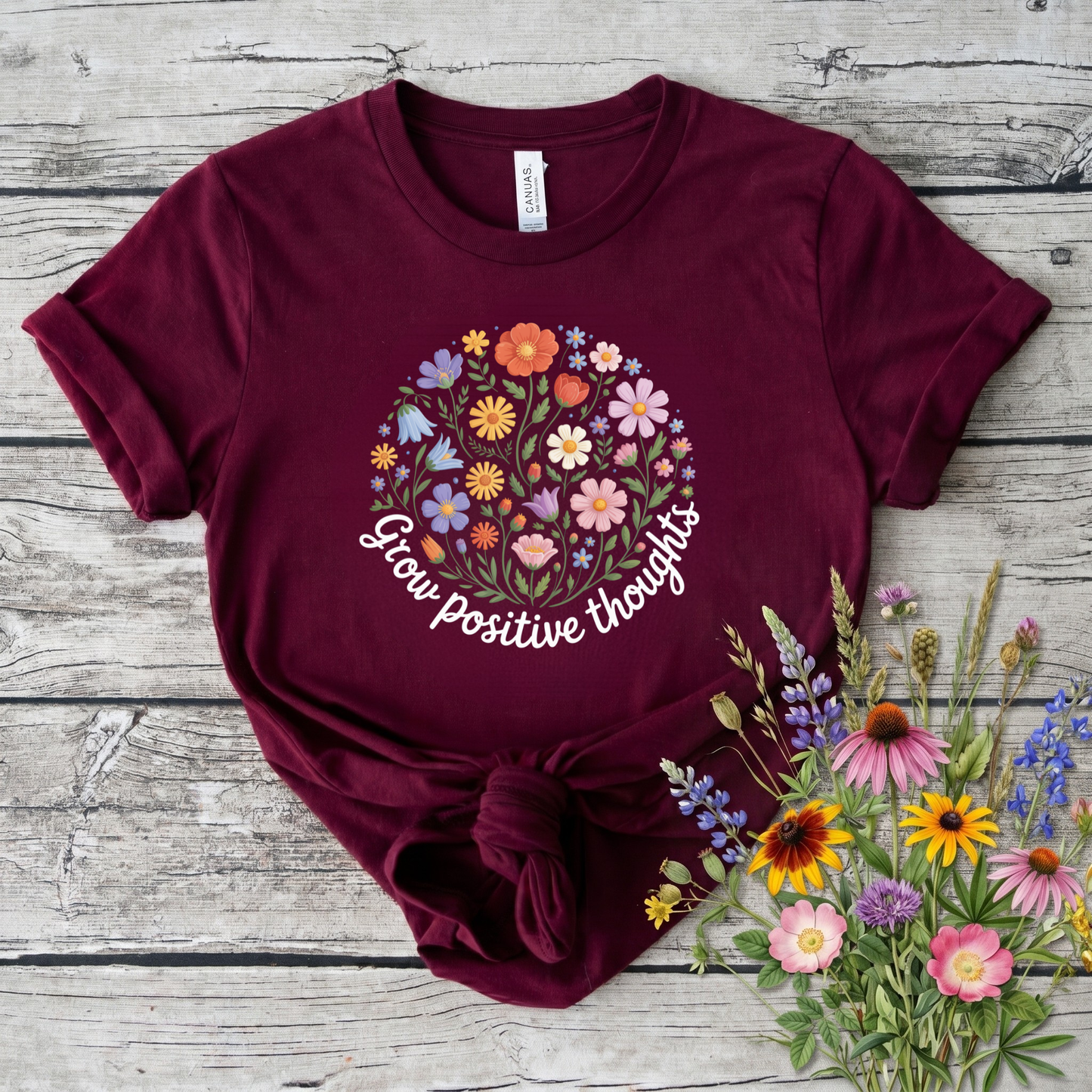  t-shirt featuring a colorful wildflower bouquet design with the inspirational phrase "Grow Positive Thoughts" in white script lettering. grow positive thoughts shirt, positive thoughts t-shirt, inspirational floral shirt, positive mindset apparel, wildflower graphic tee, motivational t-shirt, floral quote shirt, positive vibes clothing, botanical shirt, gardener gift ideas, nature lover t-shirt, self care apparel, inspirational gift for women, uplifting graphic tee, floral aesthetic clothing