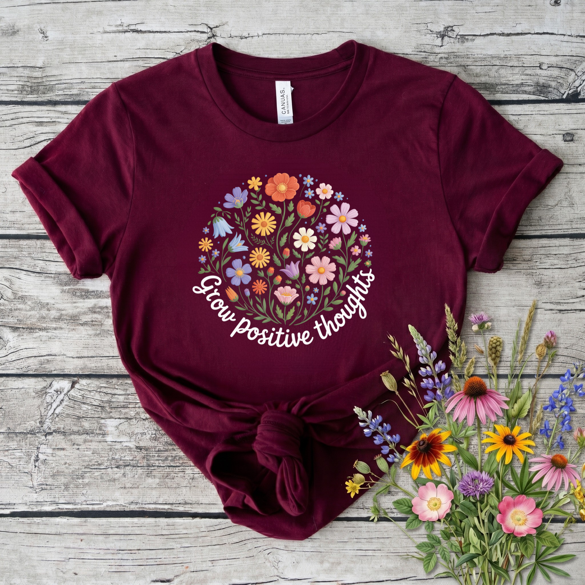  t-shirt featuring a colorful wildflower bouquet design with the inspirational phrase "Grow Positive Thoughts" in white script lettering. grow positive thoughts shirt, positive thoughts t-shirt, inspirational floral shirt, positive mindset apparel, wildflower graphic tee, motivational t-shirt, floral quote shirt, positive vibes clothing, botanical shirt, gardener gift ideas, nature lover t-shirt, self care apparel, inspirational gift for women, uplifting graphic tee, floral aesthetic clothing