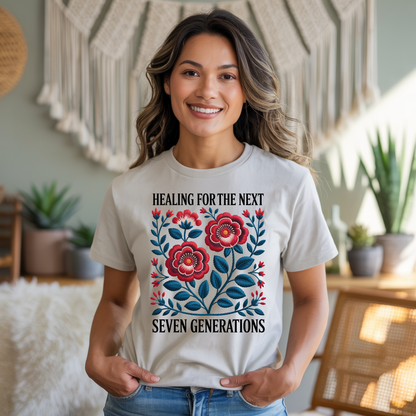 Woman wearing a t-shirt with floral design and text in a home setting that says Healing For The Next Seven Generations Indigenous Owned Shirt