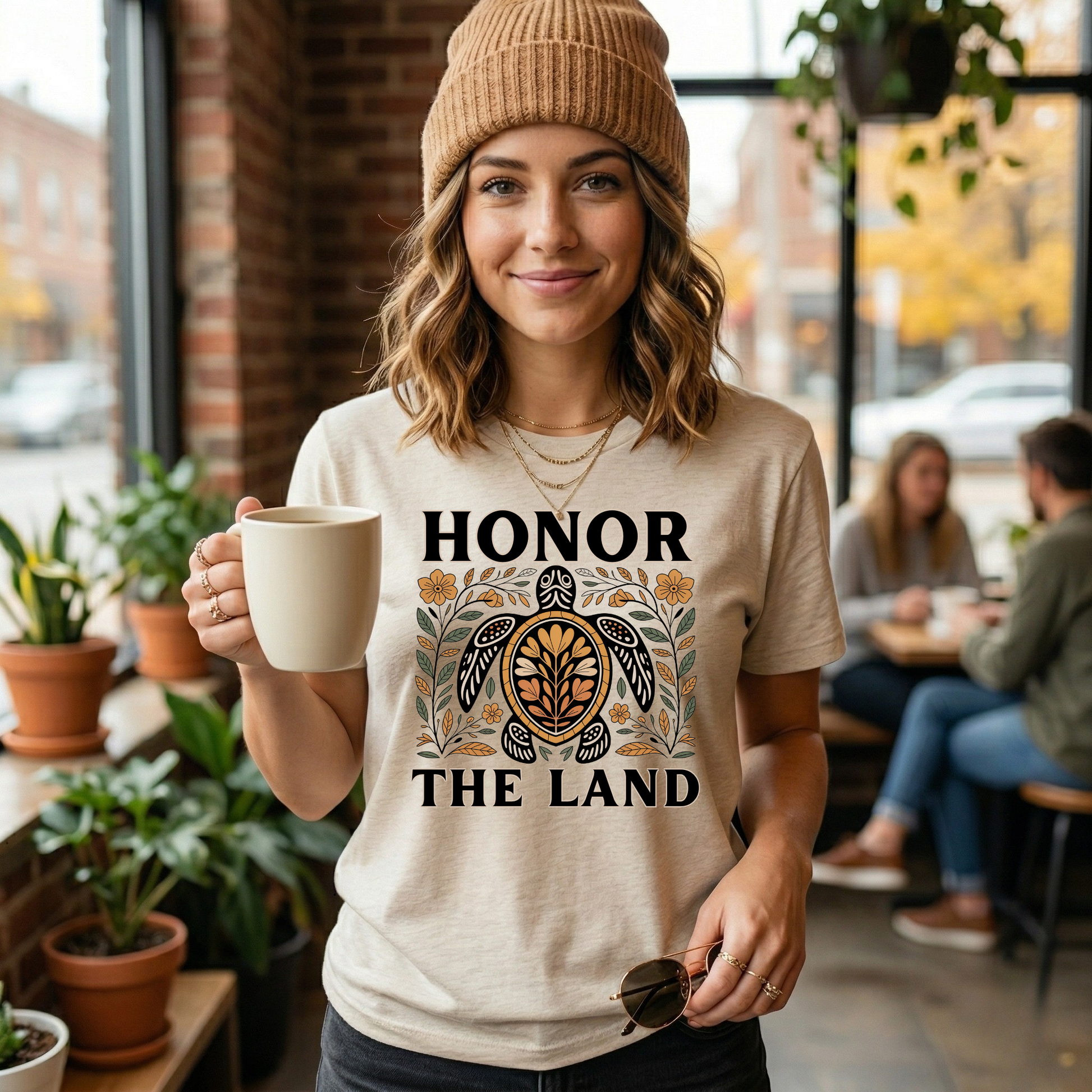 Person wearing a soft cream t-shirt with 'Honor the Land' design, honor the land turtle shirt, indigenous turtle floral shirt, indigenous designed turtle tee, land defender t-shirt, turtle symbolism indigenous apparel, floral turtle graphic tee, indigenous environmental shirt, honor the land tee, unisex indigenous shirt, indigenous owned cl
