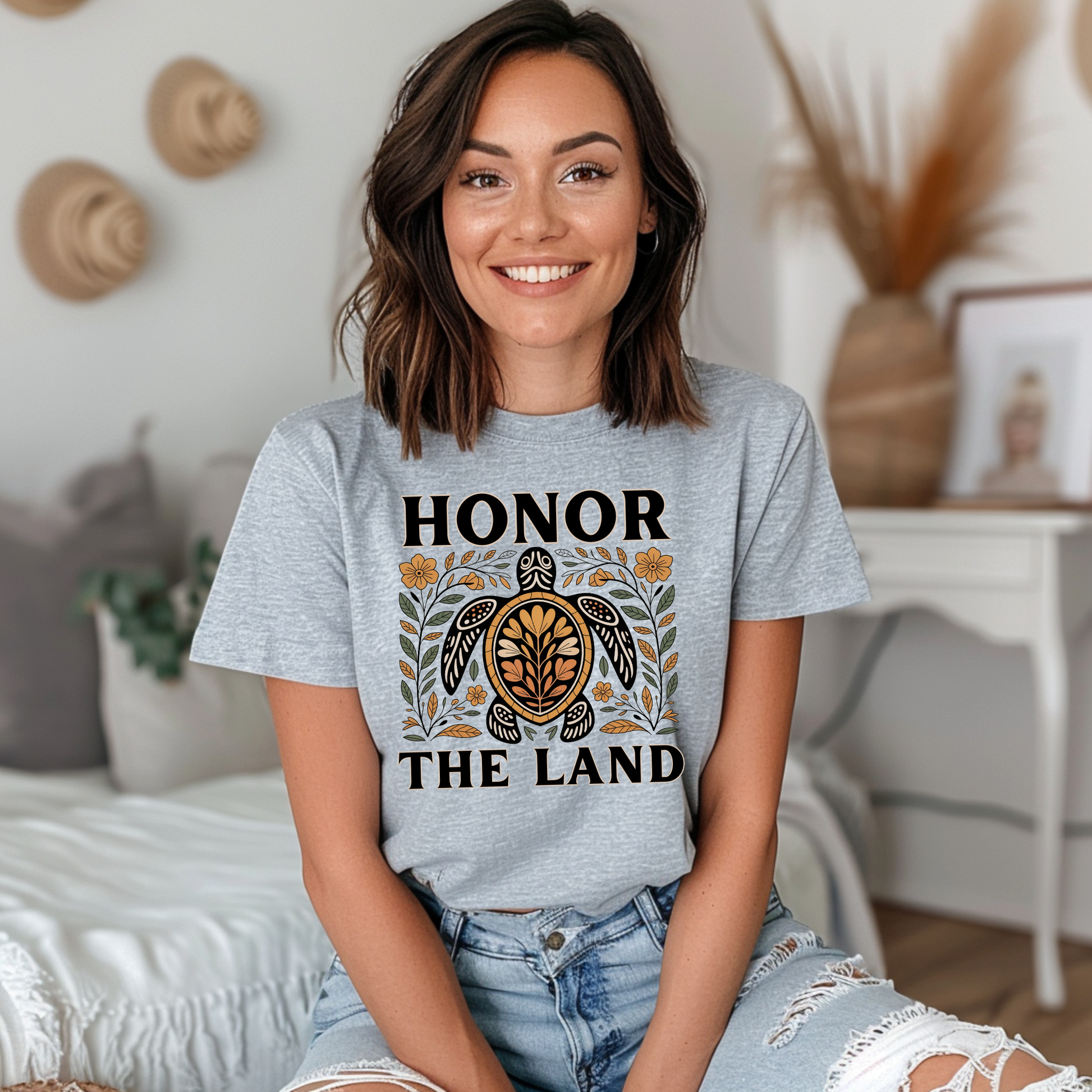 Person wearing a grey t-shirt with 'Honor the Land' design, honor the land turtle shirt, indigenous turtle floral shirt, indigenous designed turtle tee, land defender t-shirt, turtle symbolism indigenous apparel, floral turtle graphic tee, indigenous environmental shirt, honor the land tee, unisex indigenous shirt, indigenous owned cl