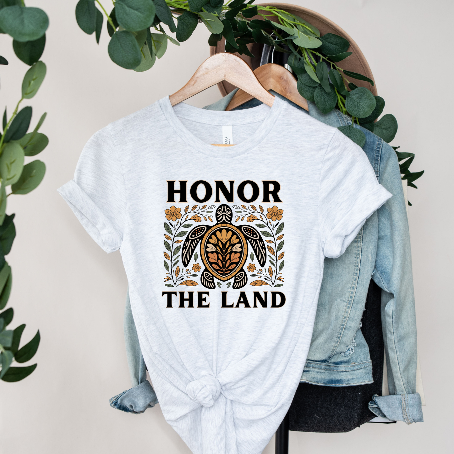 Person wearing an ash t-shirt with 'Honor the Land' design, honor the land turtle shirt, indigenous turtle floral shirt, indigenous designed turtle tee, land defender t-shirt, turtle symbolism indigenous apparel, floral turtle graphic tee, indigenous environmental shirt, honor the land tee, unisex indigenous shirt, indigenous owned cl