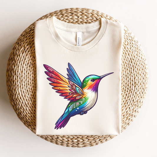 Colourful Indigenous Pride hummingbird design on cream t-shirt featuring rainbow feathers and Indigenous-inspired artwork. Indigenous Pride Shirt, Indigenous Hummingbird Shirt, LGBTQ2S+ Indigenous Apparel, Pride Hummingbird Tee, Indigenous Clothing Canada, Rainbow Hummingbird Shirt, Indigenous Designed Apparel, Native Pride Shirt, Indigenous LGBTQ Shirt