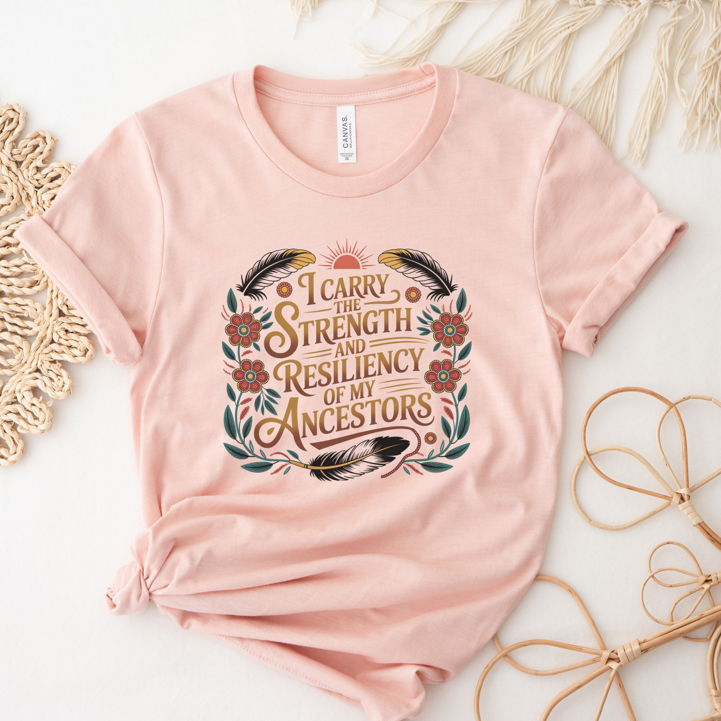 Pink t-shirt with a motivational quote on a decorative background indigenous shirt, ancestor strength shirt, resiliency shirt, indigenous inspired apparel, meaningful t shirts, strength quote shirt, heritage shirt, empowerment shirt, cultural awareness clothing, statement t shirt, social justice apparel, unity shirt, inspirational shirt, ally shirt, conscious fashion
