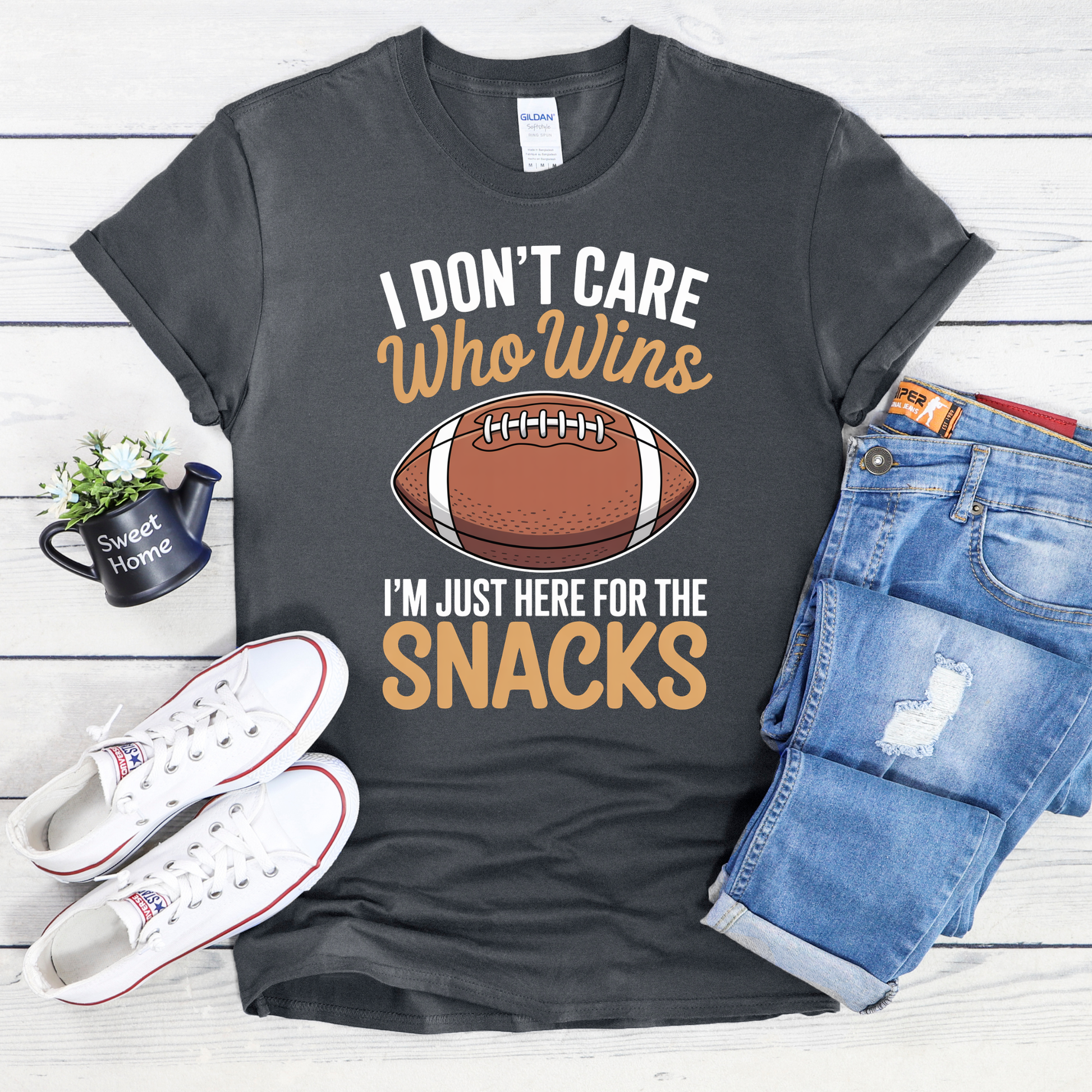 Gray t-shirt with football graphic and text, paired with white sneakers and blue jeans on a wooden surface. funny football shirt, game day shirt, snack lover shirt, super bowl party tee, I don’t care who wins shirt, here for the snacks shirt, football fan t-shirt, tailgate outfit, big game shirt, casual sports fan tee, humorous graphic tee, unisex game day top, football party clothing, lazy fan shirt, game day snacks shirt