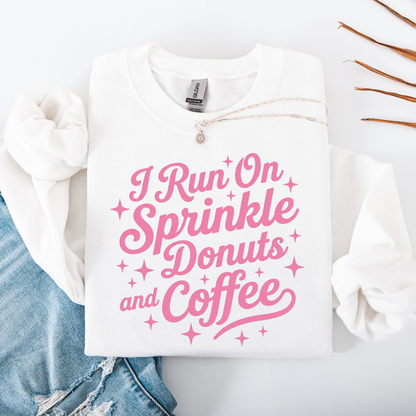White sweatshirt with pink text 'I Run On Sprinkle Donuts and Coffee' on a white background.