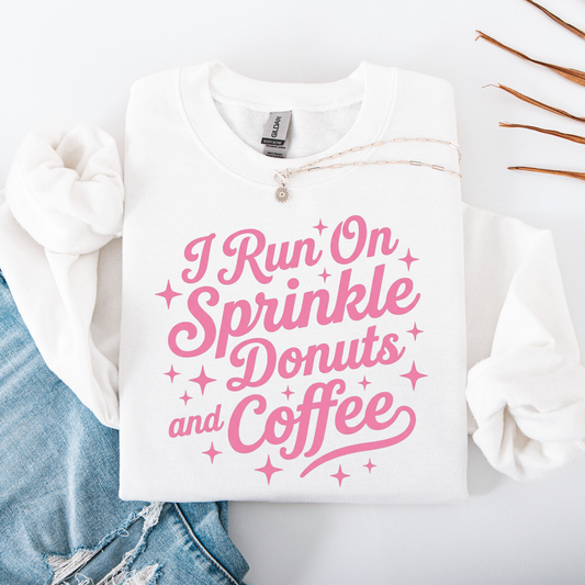 White sweatshirt with pink text 'I Run On Sprinkle Donuts and Coffee' on a white background.