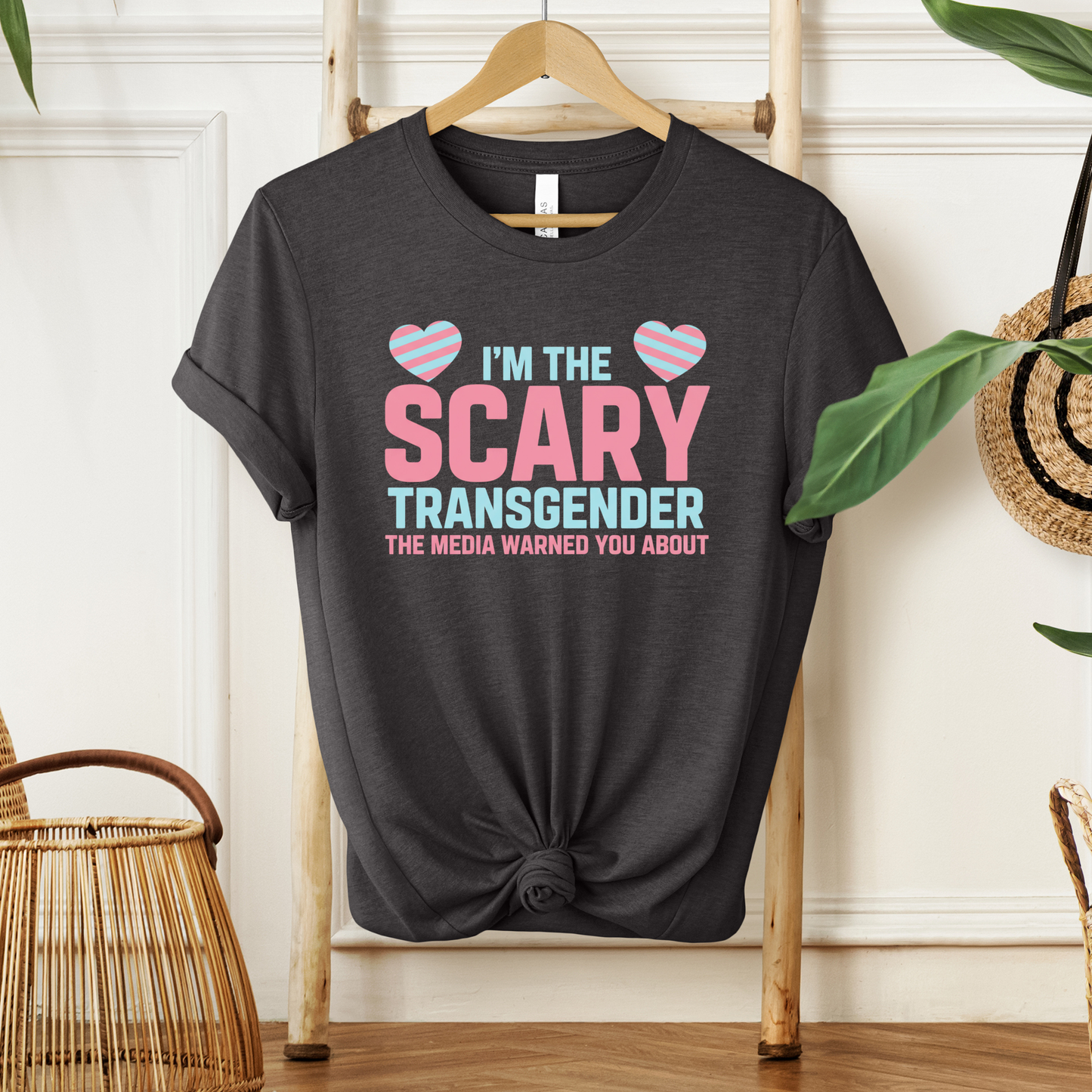 Black t-shirt with pink and blue text on a hanger against a white wall. transgender pride shirt, transgender t-shirt, LGBTQ+ clothing, trans visibility apparel, equality shirt, pride shirt for adults, trans rights clothing, LGBTQ pride tee, gender identity shirt, inclusive fashion, queer clothing brand, pride month outfit, unisex pride shirt, trans empowerment shirt, activism apparel