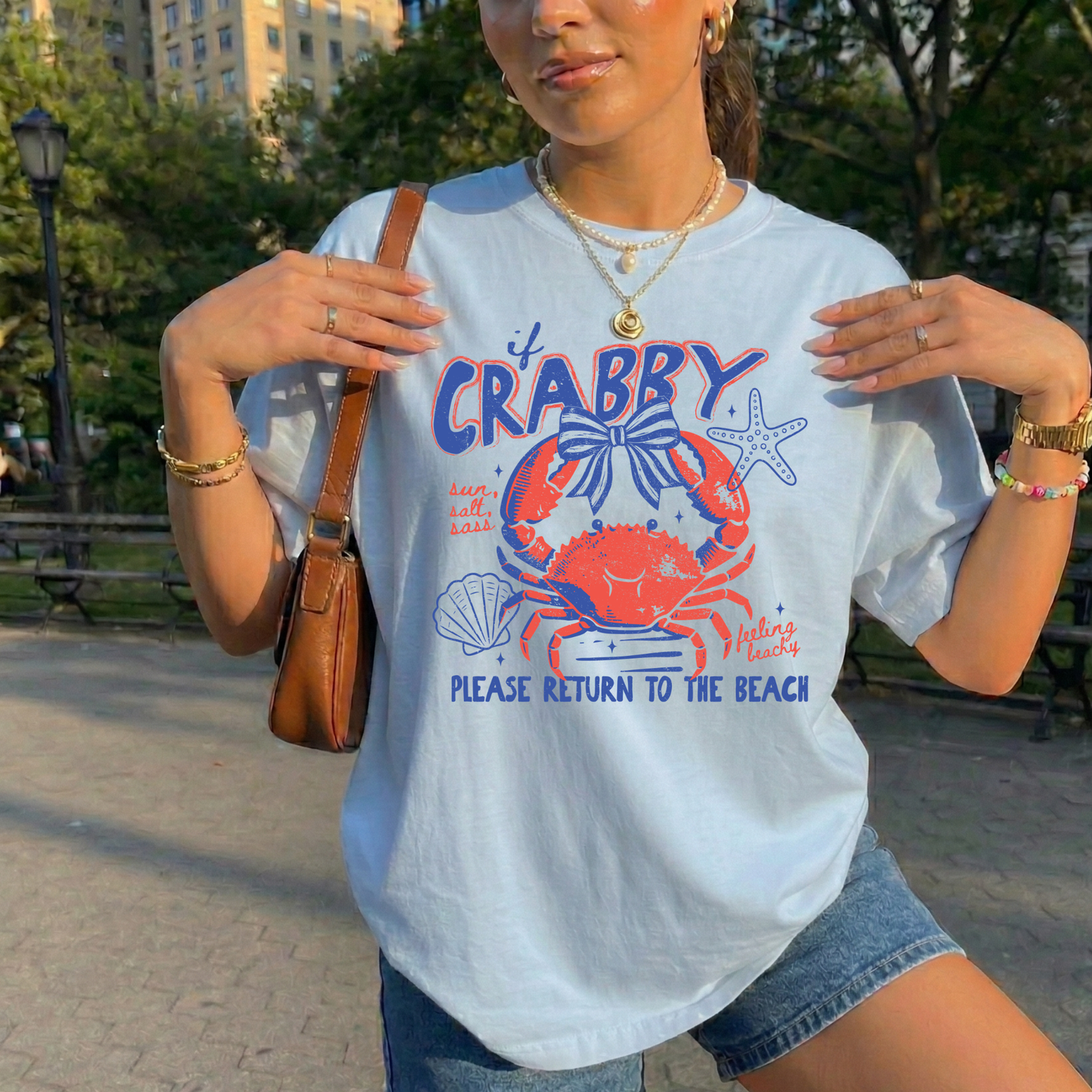 Person wearing a white t-shirt with a colorful crab graphic and text in an outdoor setting. beach shirt, coastal tee, funny beach shirt, beach vacation outfit, summer shirt, ocean lover gift, seaside apparel, crab shirt, vacation t-shirt, casual beachwear, coastal clothing, lake life shirt, beach humor tee, seaside gifts, unisex beach shirt