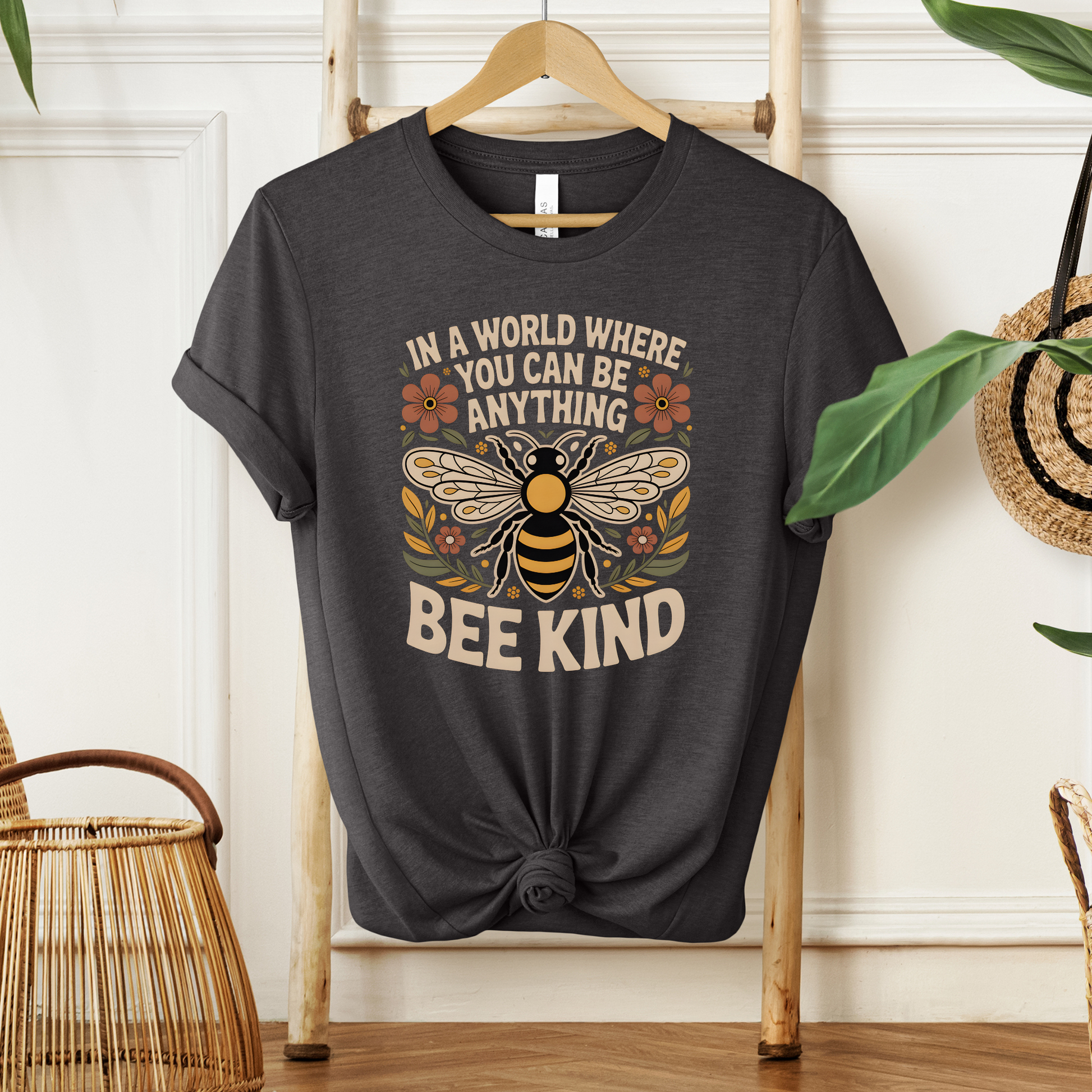 Black t-shirt with bee graphic and text on a hanger against a white wall. bee kind shirt, indigenous designed shirt, floral bee shirt, kindness shirt, inspirational t shirt, nature inspired clothing, positive message shirt, indigenous art shirt, graphic tee, unisex t shirt, gift for her, uplifting apparel