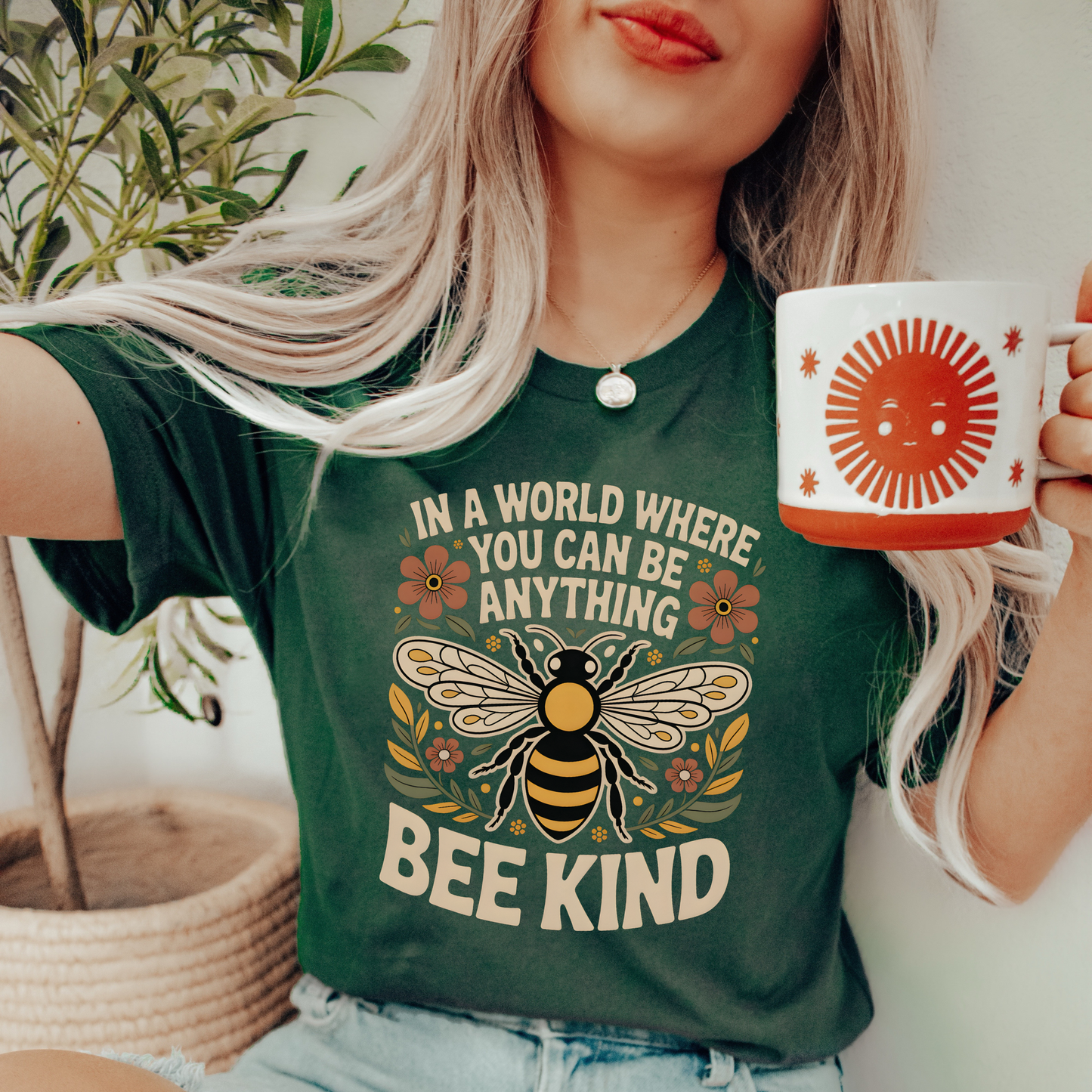 Person wearing a green t-shirt with a bee design and 'Bee Kind' text, holding a mug. bee kind shirt, indigenous designed shirt, floral bee shirt, kindness shirt, inspirational t shirt, nature inspired clothing, positive message shirt, indigenous art shirt, graphic tee, unisex t shirt, gift for her, uplifting apparel