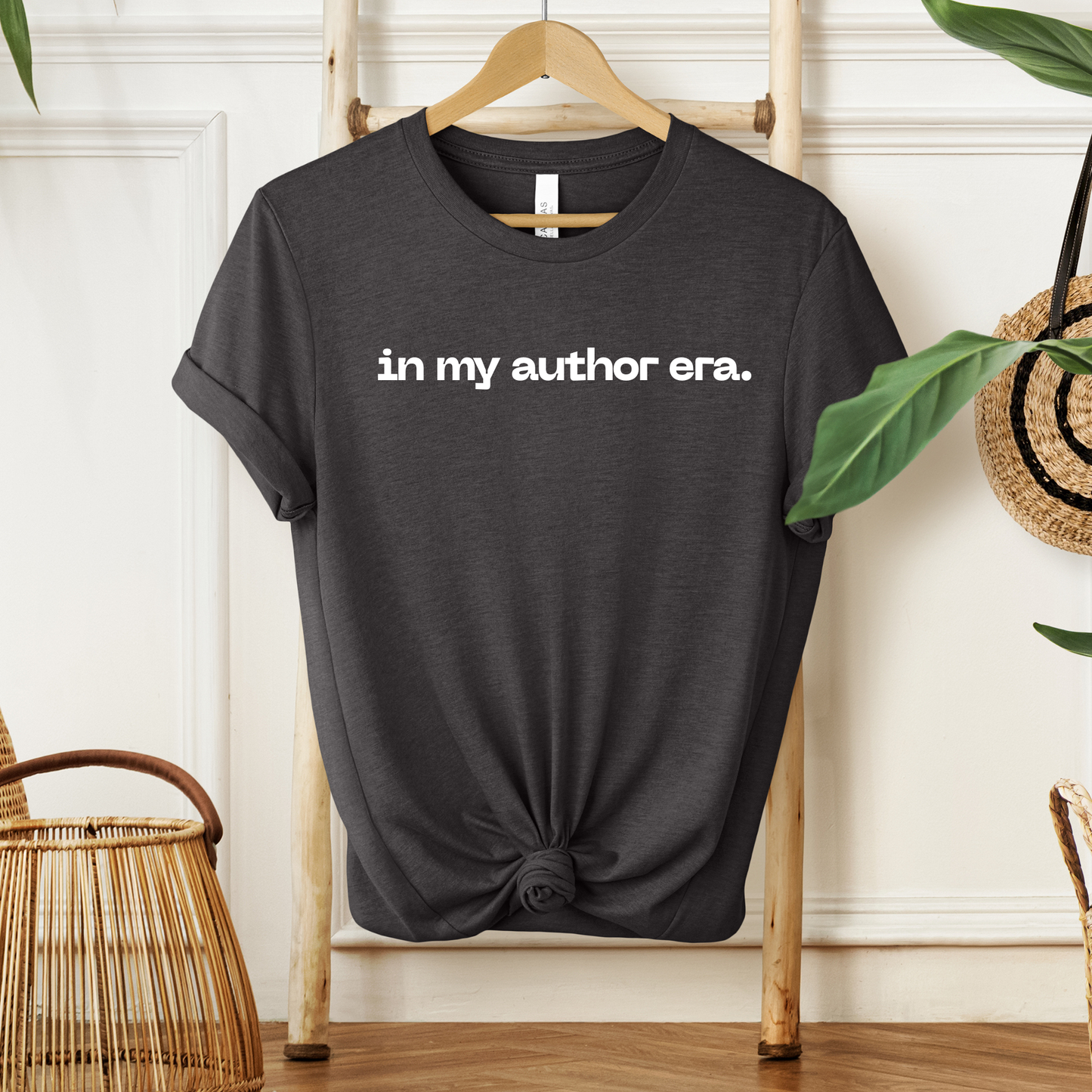 Black t-shirt with 'in my author era.' text on a hanger against a neutral wall. in my author era shirt, writer shirt, author tee, writing shirt, nanowrimo shirt, book author apparel, novelist shirt, writer gift shirt, author era tee, creative writer clothing, book launch shirt, writing community tee, aspiring author shirt, fiction writer apparel, manuscript shirt