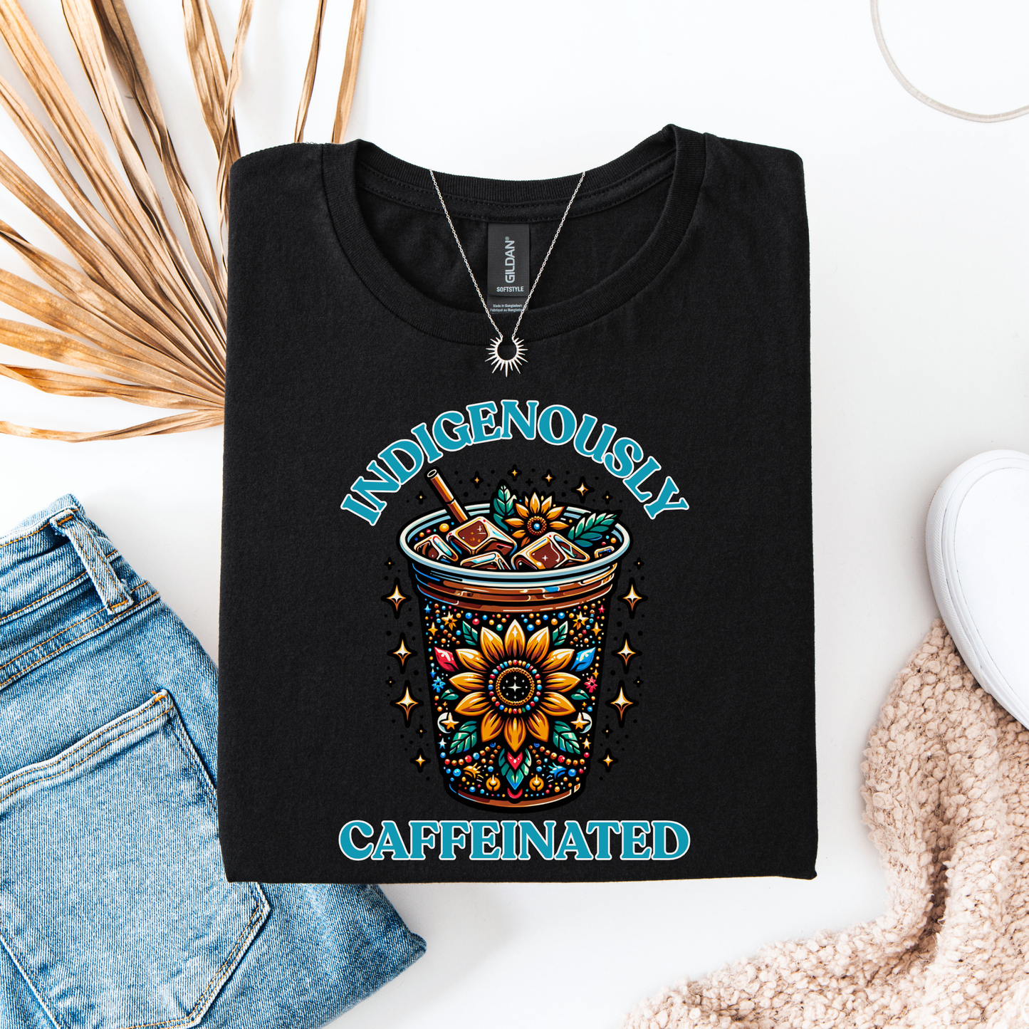 t-shirt featuring a vibrant Indigenous-inspired floral iced coffee design with the phrase "Indigenously Caffeinated" in turquoise lettering. indigenously caffeinated shirt, indigenous coffee lover shirt, indigenous graphic tee, native coffee shirt, coffee lover apparel, indigenous pride clothing, floral coffee design shirt, indigenous entrepreneur shirt, caffeine lover gift, indigenous fashion canada, indigenous art t-shirt, iced coffee graphic tee, indigenous gift ideas, coffee addict shirt, indigenous sma