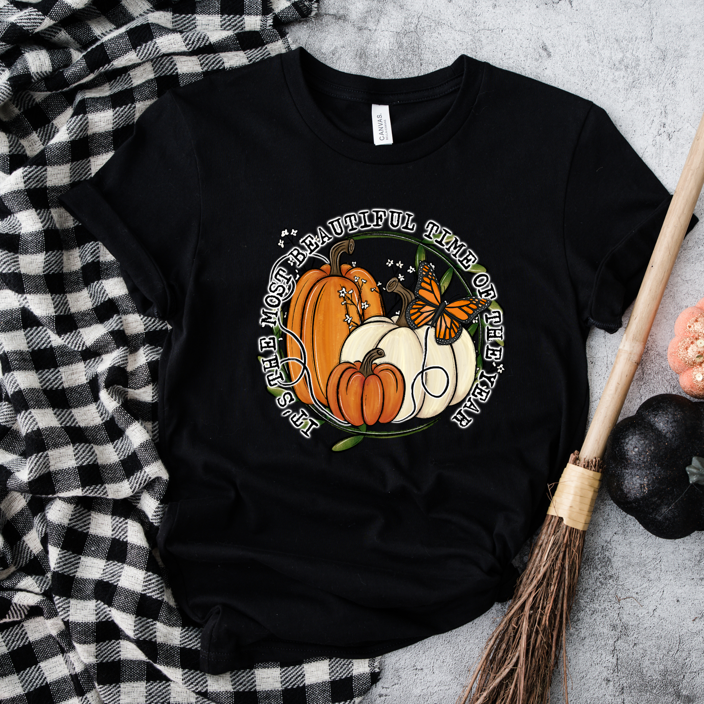 unisex t-shirt featuring pumpkins, a monarch butterfly, leafy accents, and the phrase "It's The Most Beautiful Time Of The Year" in a circular autumn-inspired design. it's the most beautiful time of the year shirt, fall shirt, autumn shirt, pumpkin shirt, pumpkin season shirt, thanksgiving shirt, fall graphic tee, cozy autumn shirt, pumpkin patch shirt, sweater weather shirt, fall aesthetic, harvest shirt, halloween shirt, pumpkin lover gift, autumn outfit, farmhouse fall decor shirt, monarch butterfly
