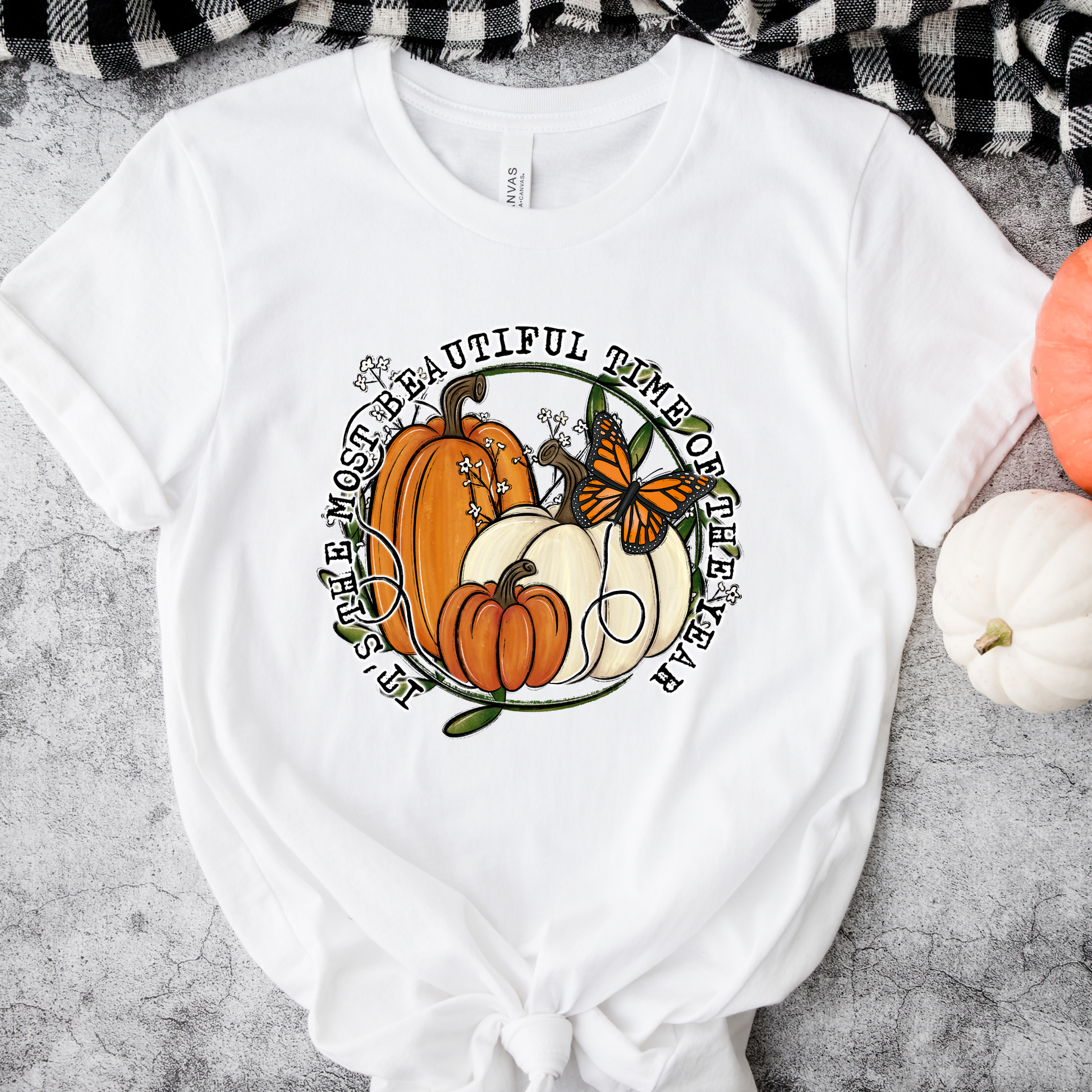 unisex t-shirt featuring pumpkins, a monarch butterfly, leafy accents, and the phrase "It's The Most Beautiful Time Of The Year" in a circular autumn-inspired design. it's the most beautiful time of the year shirt, fall shirt, autumn shirt, pumpkin shirt, pumpkin season shirt, thanksgiving shirt, fall graphic tee, cozy autumn shirt, pumpkin patch shirt, sweater weather shirt, fall aesthetic, harvest shirt, halloween shirt, pumpkin lover gift, autumn outfit, farmhouse fall decor shirt, monarch butterfly