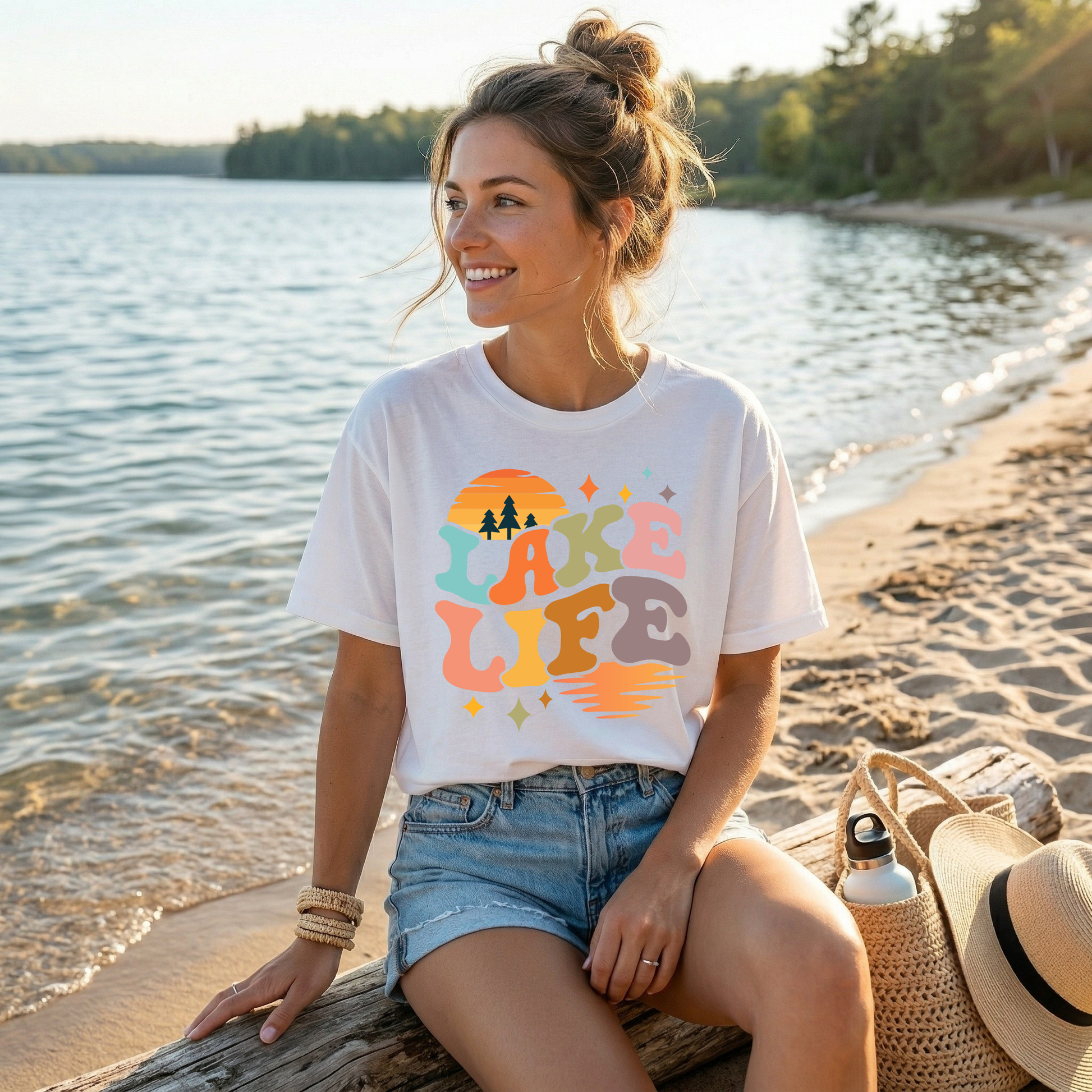 Woman wearing a 'Lake Life' t-shirt sitting by a lake. lake life shirt, lake life tee, retro lake graphic shirt, sunset lake shirt, boating shirt, lake lover apparel, summer lake tee, unisex lake life clothing, lake house gift, fishing shirt, cottage lake outfit, lake vacation tee, boater shirt, lakeside apparel, retro sunset graphic tee