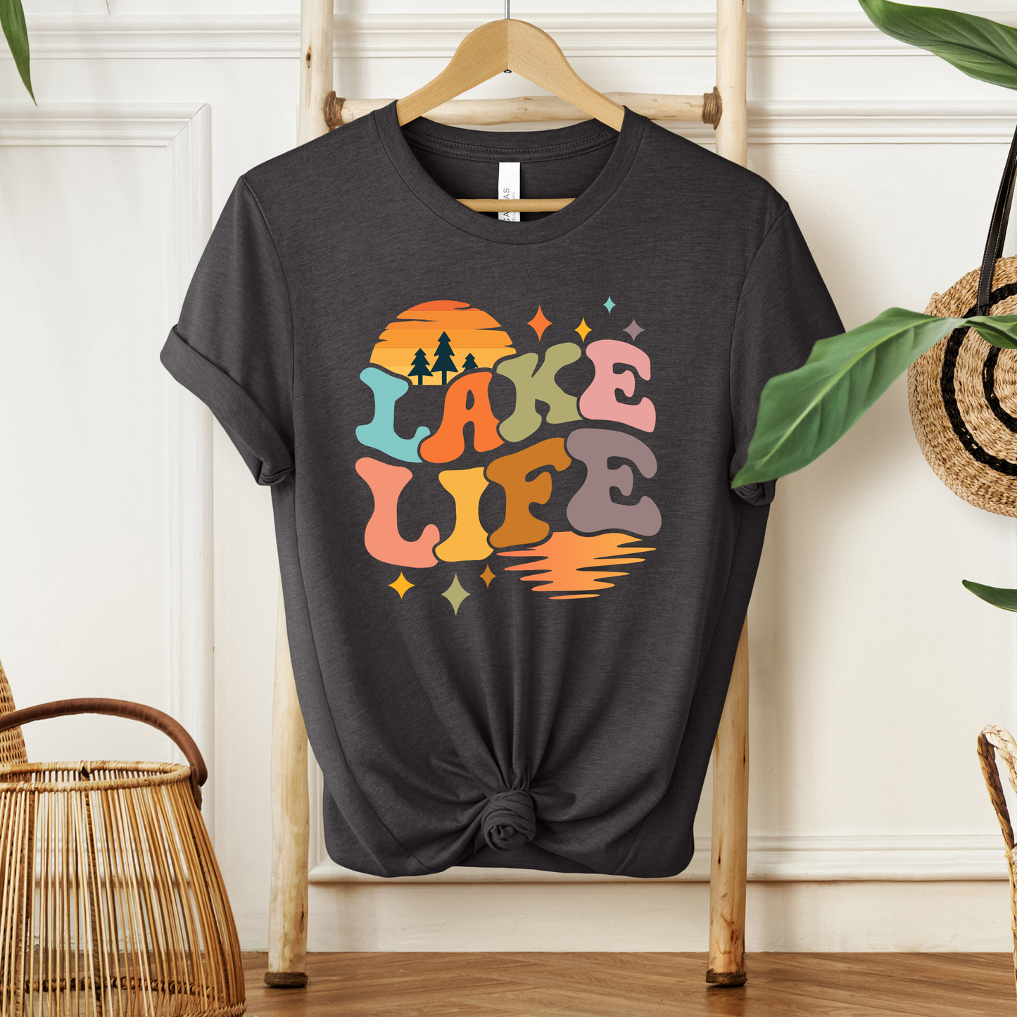 Black t-shirt with 'Lake Life' design on a wooden hanger against a white wall. lake life shirt, lake life tee, retro lake graphic shirt, sunset lake shirt, boating shirt, lake lover apparel, summer lake tee, unisex lake life clothing, lake house gift, fishing shirt, cottage lake outfit, lake vacation tee, boater shirt, lakeside apparel, retro sunset graphic tee