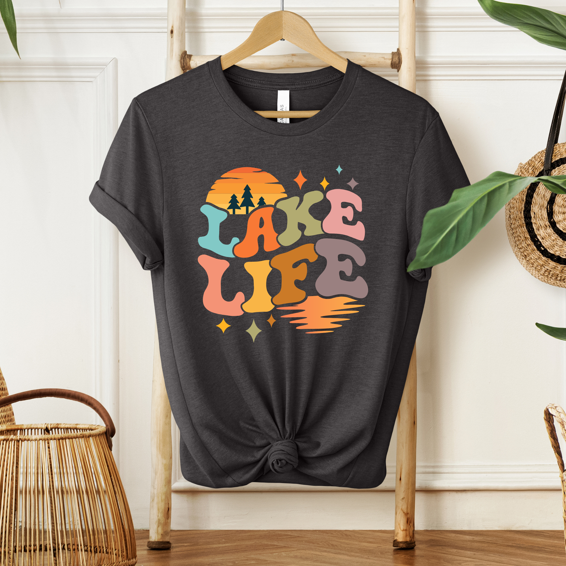Black t-shirt with 'Lake Life' design on a wooden hanger against a white wall. lake life shirt, lake life tee, retro lake graphic shirt, sunset lake shirt, boating shirt, lake lover apparel, summer lake tee, unisex lake life clothing, lake house gift, fishing shirt, cottage lake outfit, lake vacation tee, boater shirt, lakeside apparel, retro sunset graphic tee