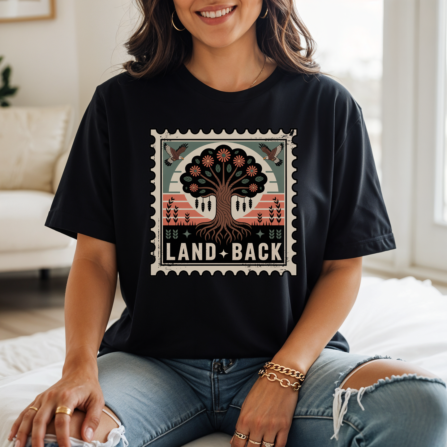 Person wearing a black t-shirt with a graphic design and text, sitting indoors. land back shirt, indigenous awareness shirt, nature shirt, tree graphic tee, minimalist shirt, advocacy apparel, eco conscious clothing, indigenous inspired apparel, social justice shirt, unisex t shirt, earthy aesthetic clothing, statement tee