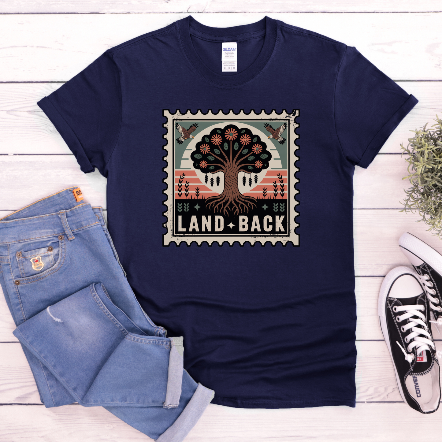 Navy blue t-shirt with a graphic design and text, paired with jeans and sneakers on a wooden surface. land back shirt, indigenous awareness shirt, nature shirt, tree graphic tee, minimalist shirt, advocacy apparel, eco conscious clothing, indigenous inspired apparel, social justice shirt, unisex t shirt, earthy aesthetic clothing, statement tee
