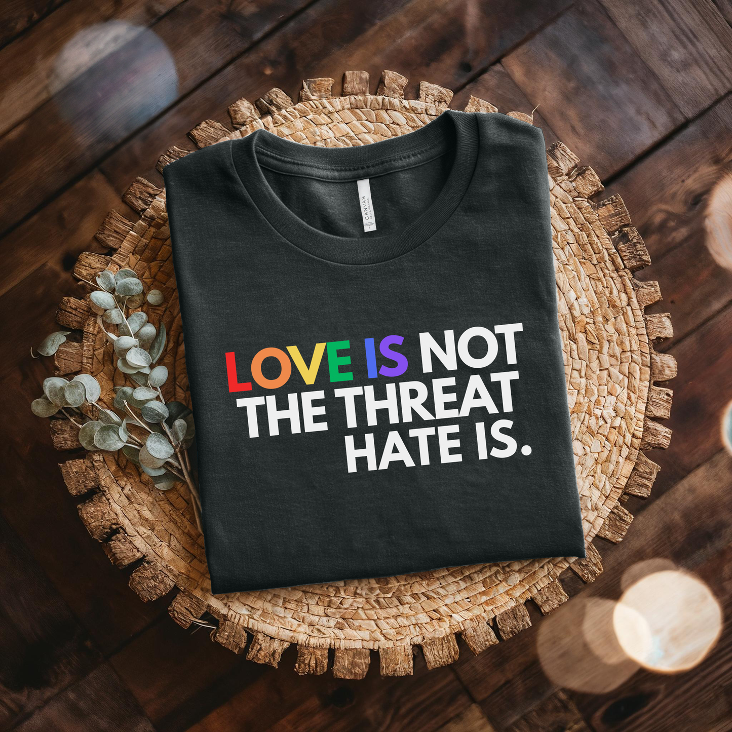 t-shirt featuring the phrase "Love Is Not The Threat Hate Is." with rainbow-colored lettering for Love, promoting LGBTQ+ pride, equality, and inclusion. love is not the threat hate is shirt, pride shirt, pride ally shirt, LGBTQ shirt, LGBTQ ally, equality shirt, love wins shirt, rainbow shirt, inclusive apparel, human rights shirt, kindness shirt, acceptance shirt, pride month shirt, ally gift, social justice shirt, equality tee, progressive apparel, support LGBTQ, activist shirt, inclusive graphic tee