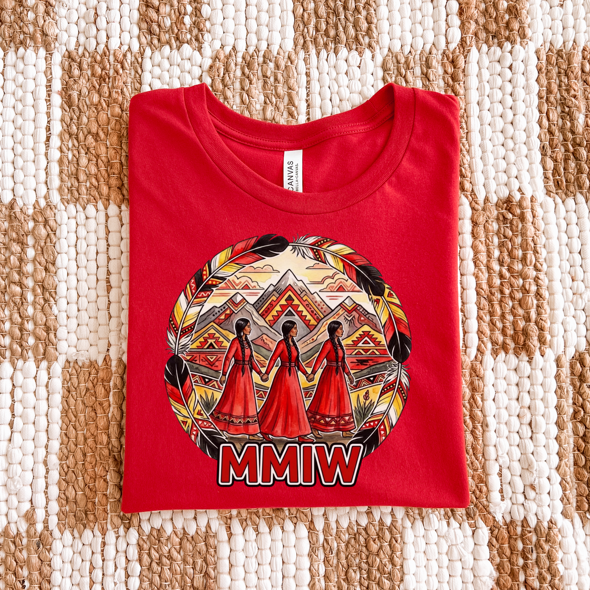 Red t-shirt with a graphic design and 'MMIW' text on a textured surface. The MMIW Feather Frame Unisex T-Shirt is a meaningful Indigenous awareness shirt designed to honor Missing and Murdered Indigenous Women, Girls, and Two-Spirit people. MMIW shirt, MMIW awareness, Indigenous t shirt, Missing and Murdered Indigenous Women, Indigenous graphic tee, Indigenous awareness shirt, unisex t shirt, activism shirt, Indigenous justice, Two Spirit awareness, Native apparel, awareness tee, Indigenous owned brand, fea