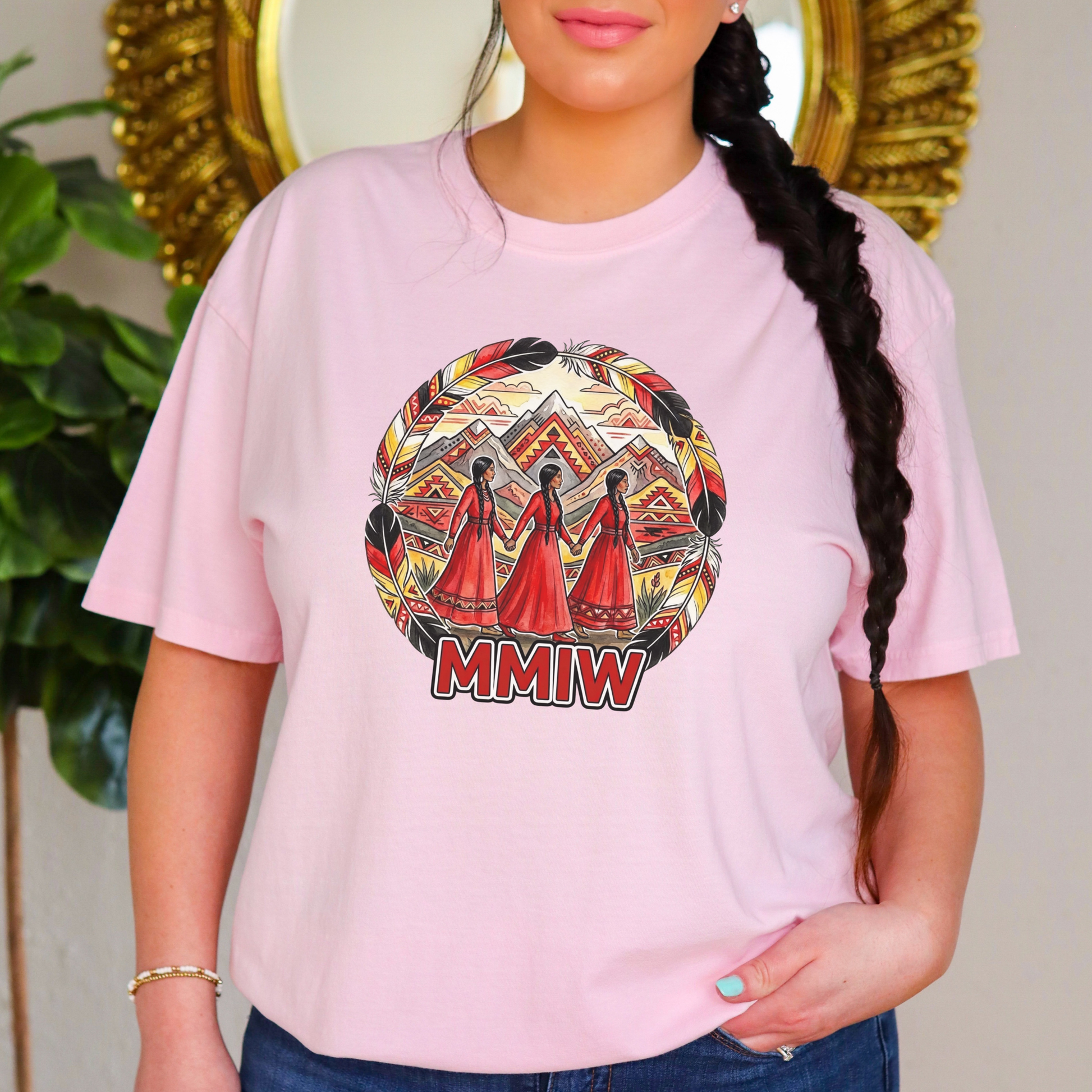 Person wearing a pink t-shirt with a colorful graphic and 'MMIW' text, standing in front of a decorative mirror. MMIW shirt, MMIW awareness, Indigenous t shirt, Missing and Murdered Indigenous Women, Indigenous graphic tee, Indigenous awareness shirt, unisex t shirt, activism shirt, Indigenous justice, Two Spirit awareness, Native apparel, awareness tee, Indigenous owned brand, feather frame shirt, statement t shirt