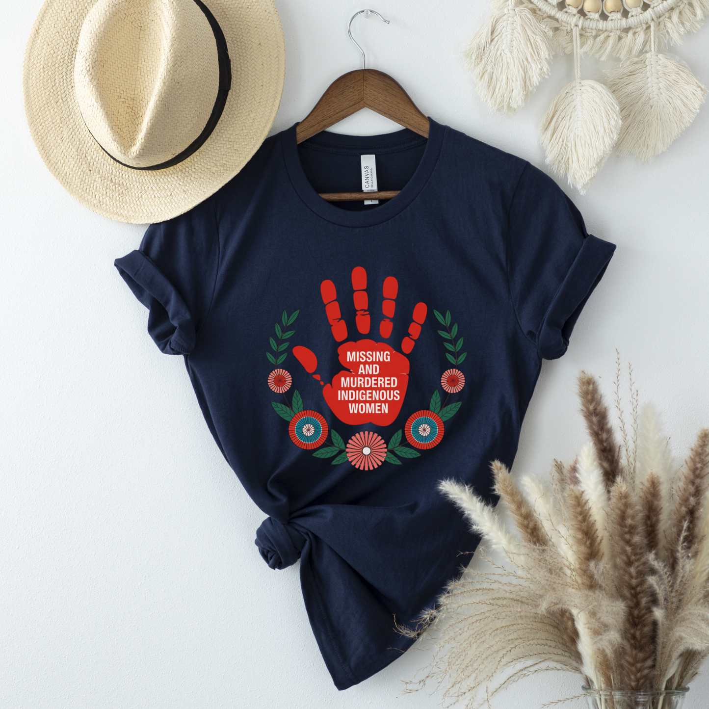 Navy blue t-shirt with red handprint design and text on a white surface with decorative items. MMIW shirt, Missing and Murdered Indigenous Women shirt, red handprint shirt, Indigenous awareness shirt, Indigenous rights shirt, MMIW awareness tee, solidarity shirt, social justice shirt, unisex awareness shirt, Canada Indigenous shirt, Indigenous activism clothing, reconciliation shirt, advocate shirt, meaningful graphic tee, awareness apparel